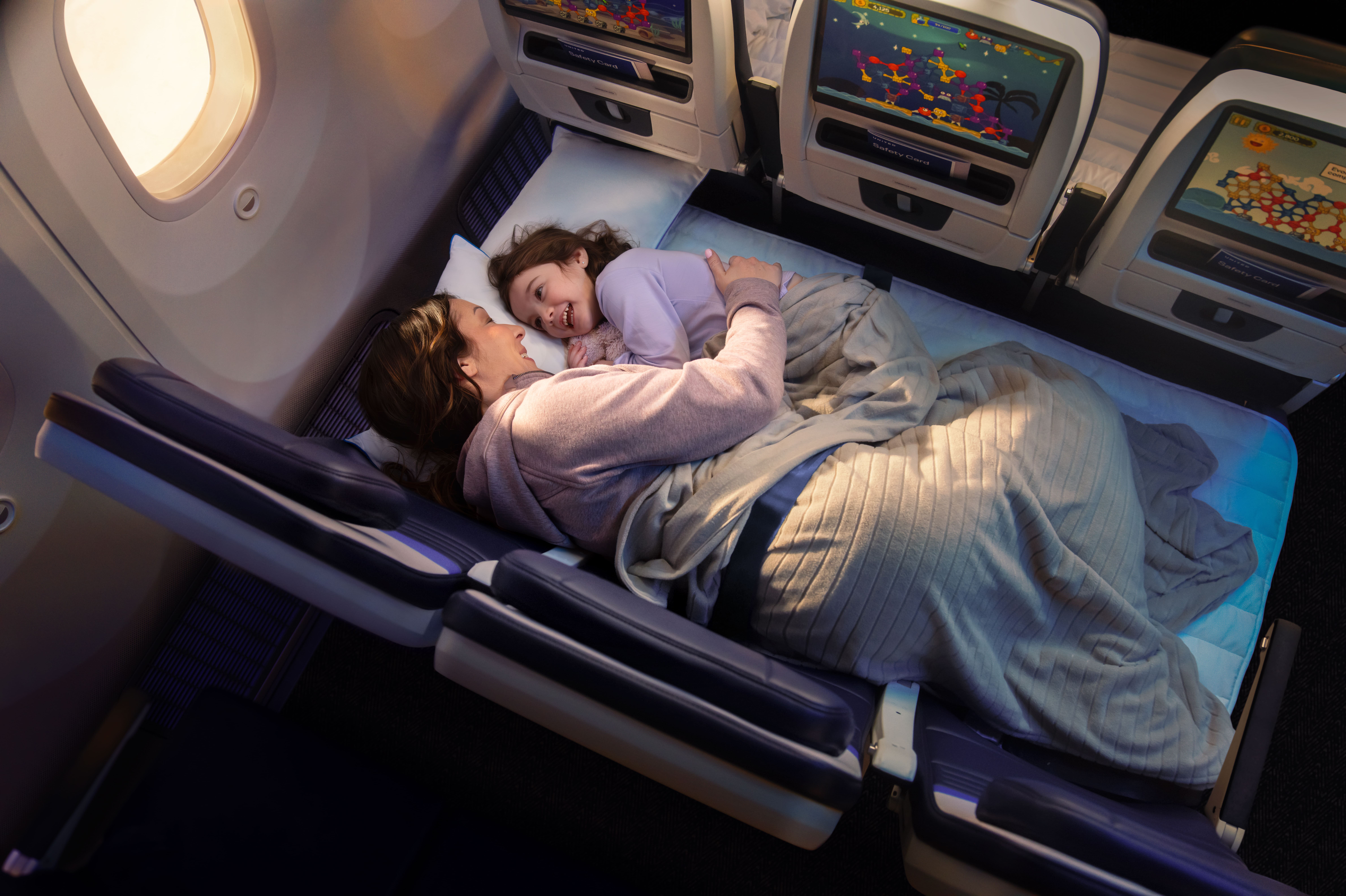 United Airlines Relax Row with a mother and child sleeping on the flat couch surface in economy class
