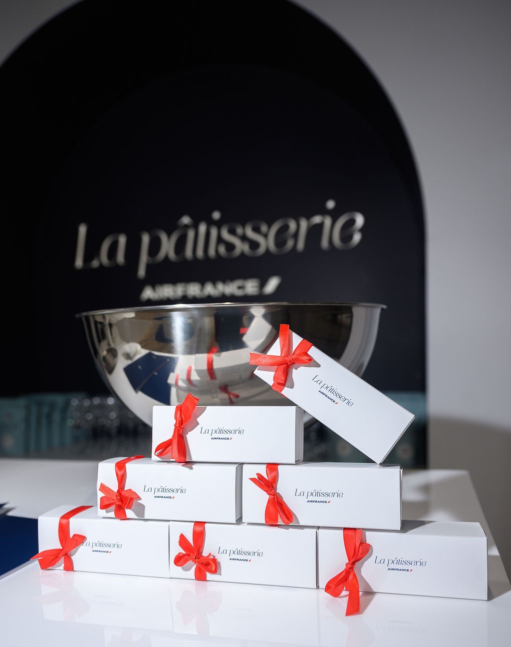 Stack of branded La pâtisserie take-out boxes tied with red ribbons