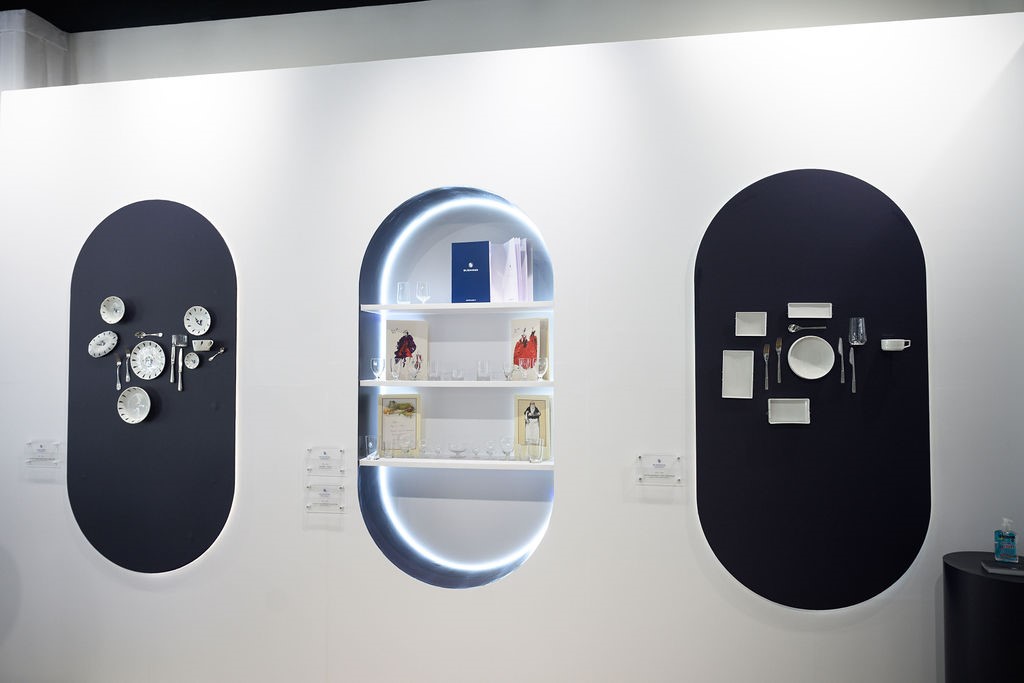 Three oval display cabinets at the pop-up showing vintage Air France menus, china, and glassware