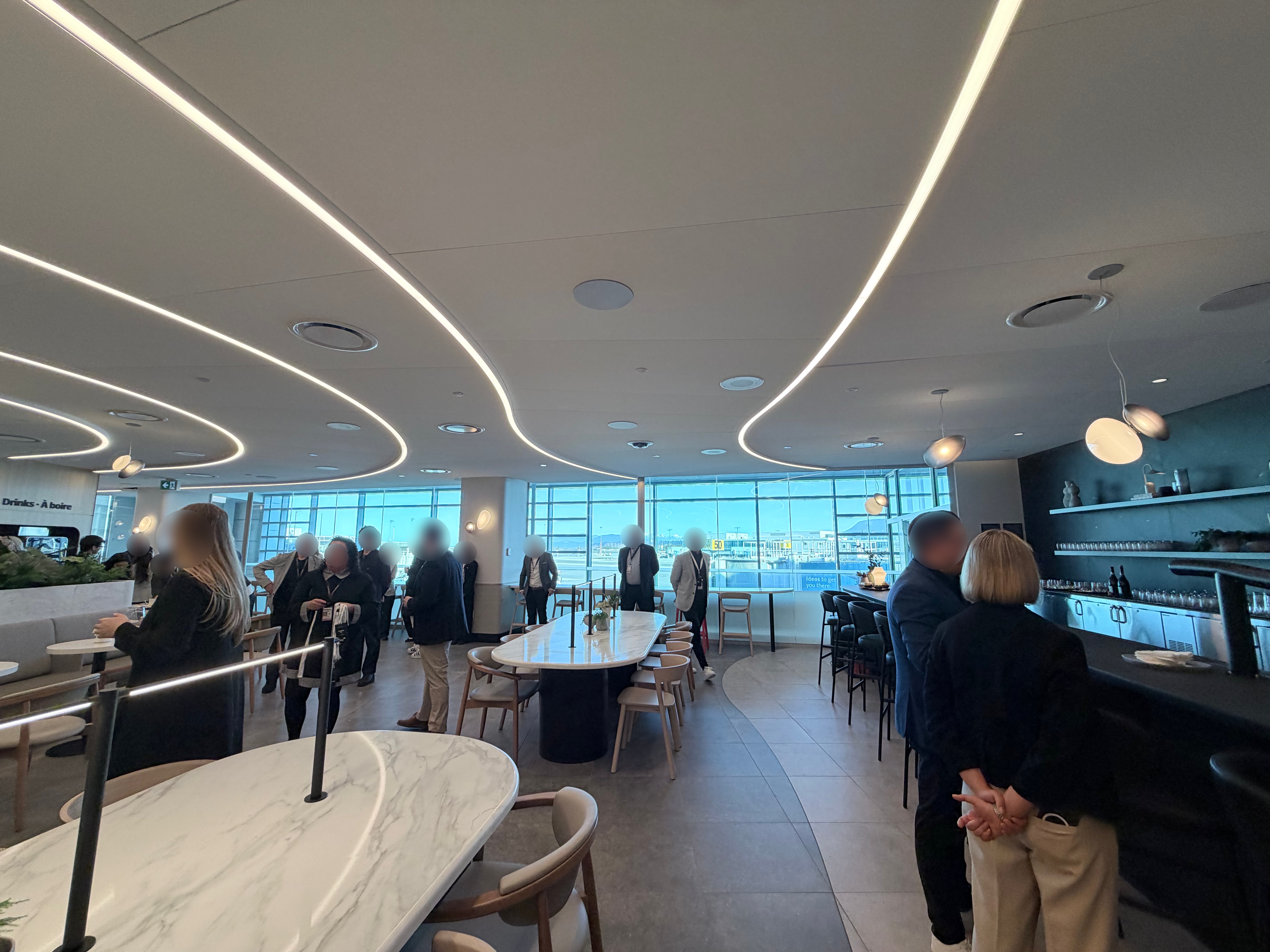 Interior of the Air Canada Café at YVR Gate C50 with flowing ceiling lights, marble tables, and full-height windows