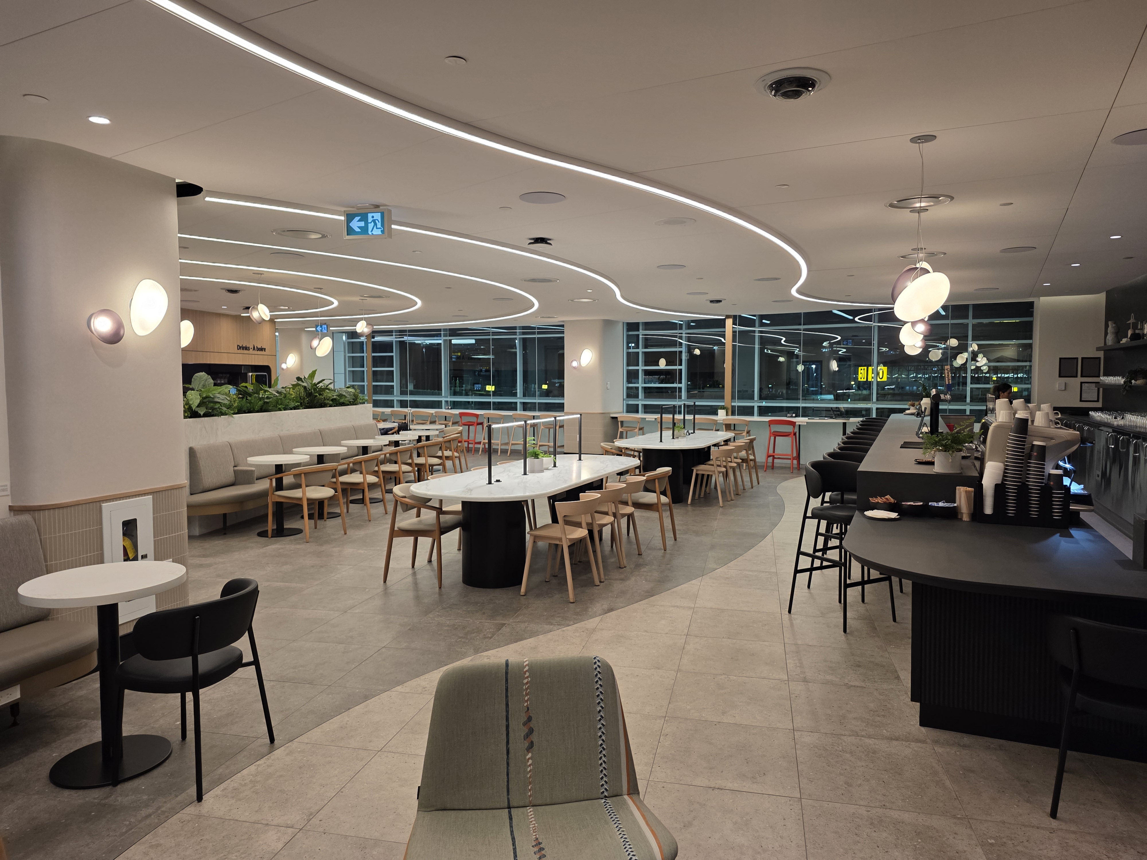Wide panoramic view of the full Air Canada Café at YVR Gate C50 showing bar, seating, windows, and LED ceiling lights