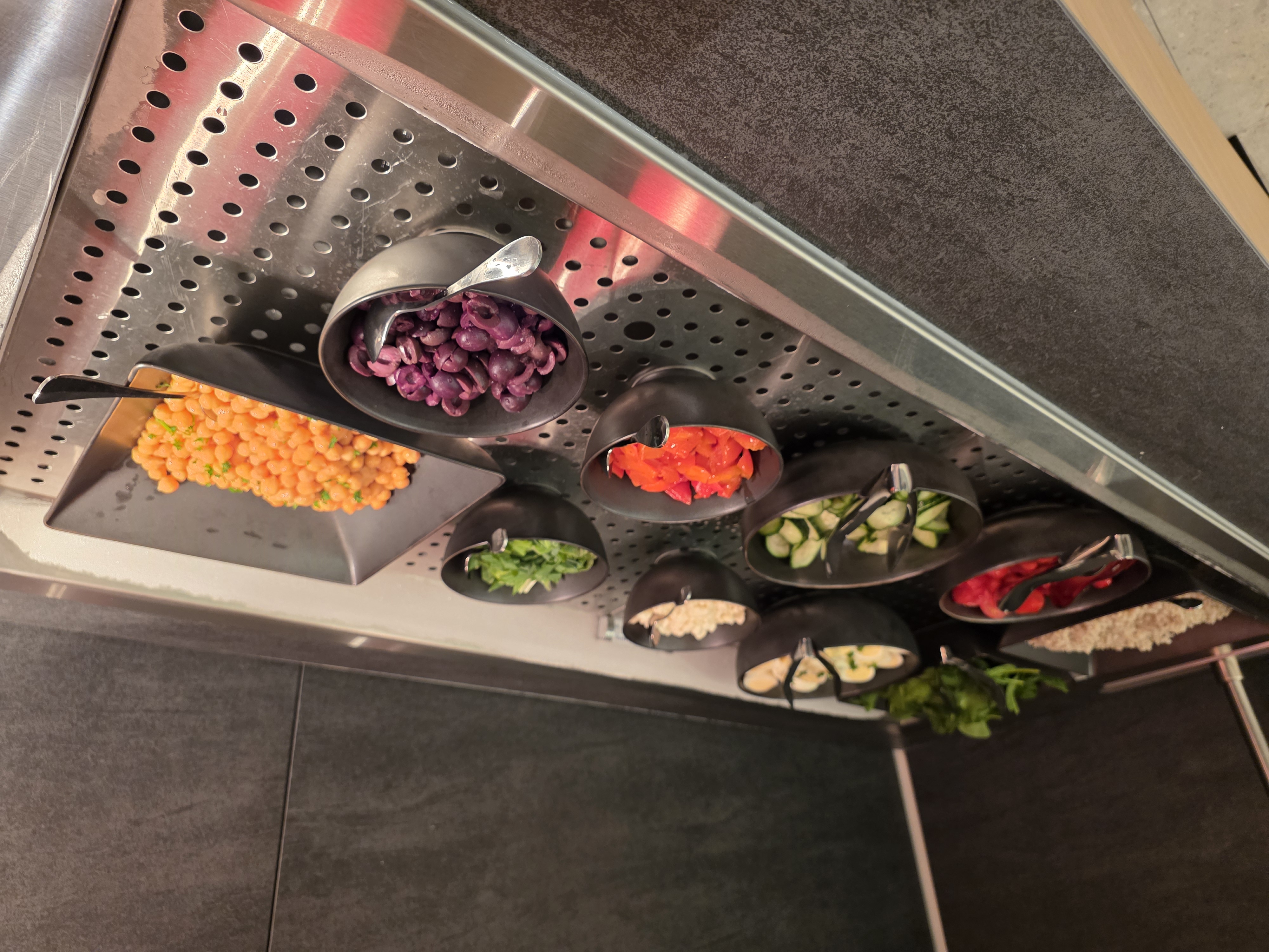 Salad bar and toppings station with fresh vegetables at the Air Canada Café YVR