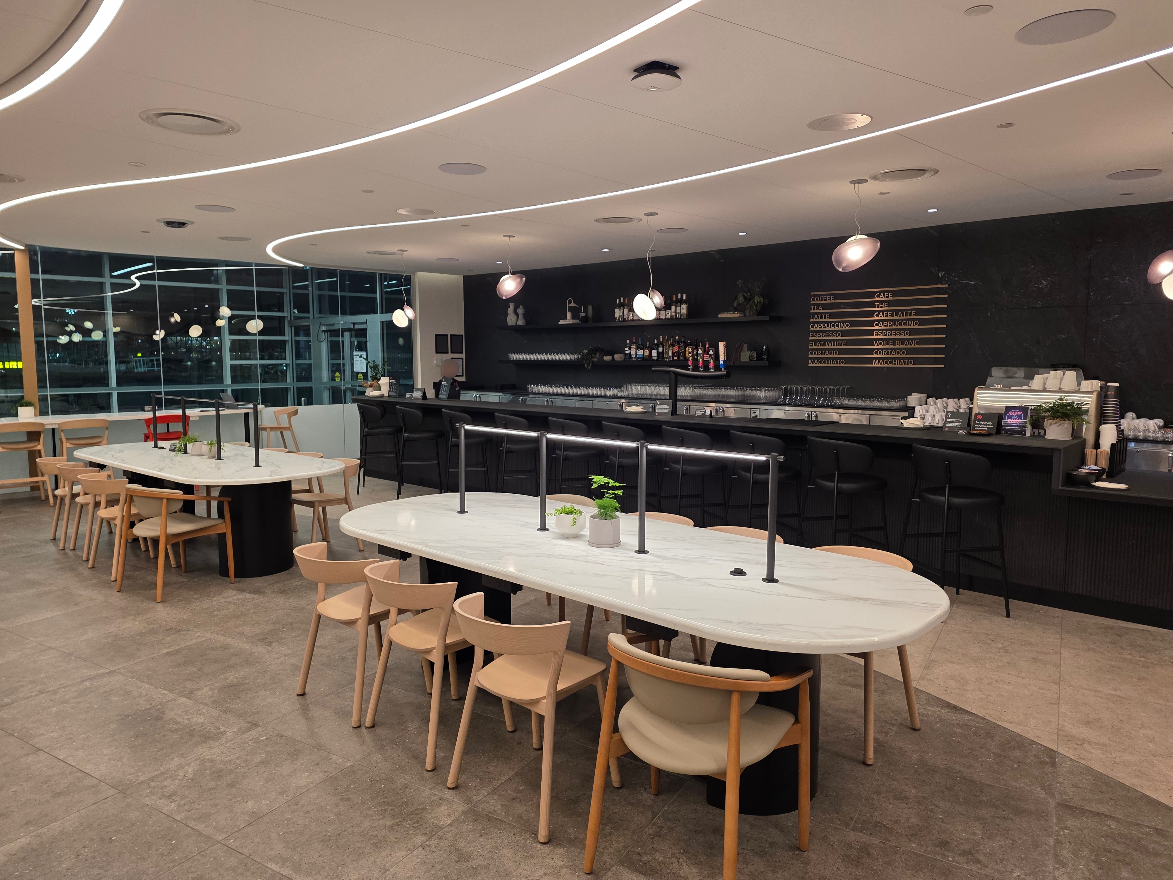 Bar area at the Air Canada Café YVR with marble communal tables and dark slate backdrop