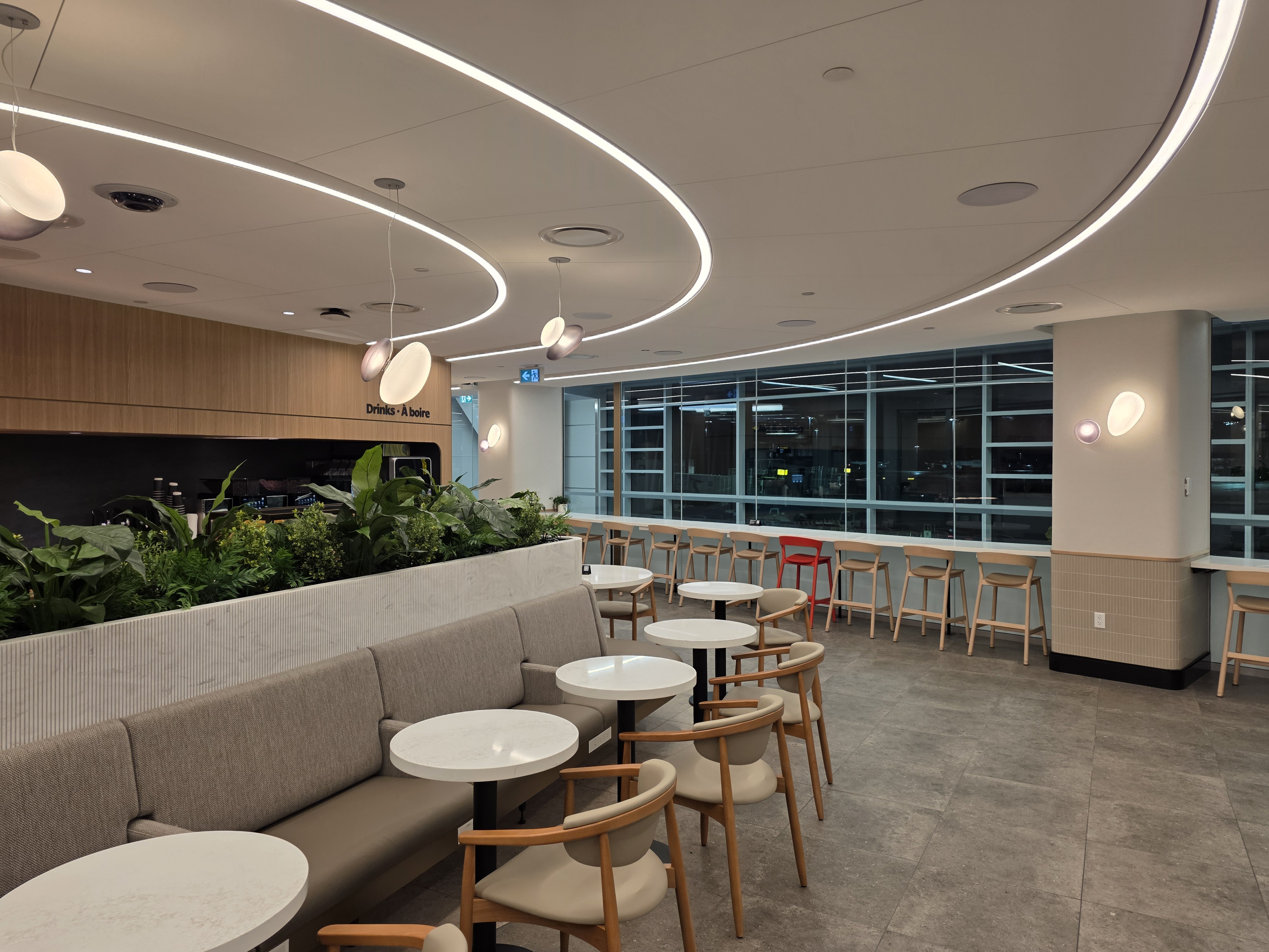 Banquette seating area with flowing LED ceiling lights and full-height windows at the Air Canada Café YVR