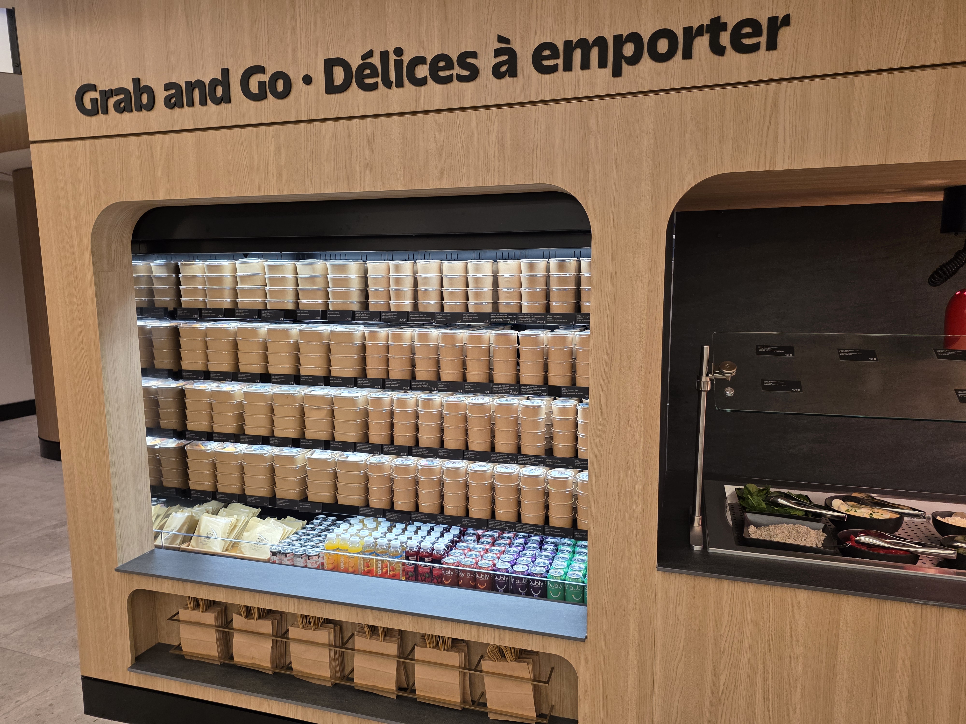 Grab and Go wall with pre-packaged bowls, drinks, and sandwiches at the Air Canada Café YVR