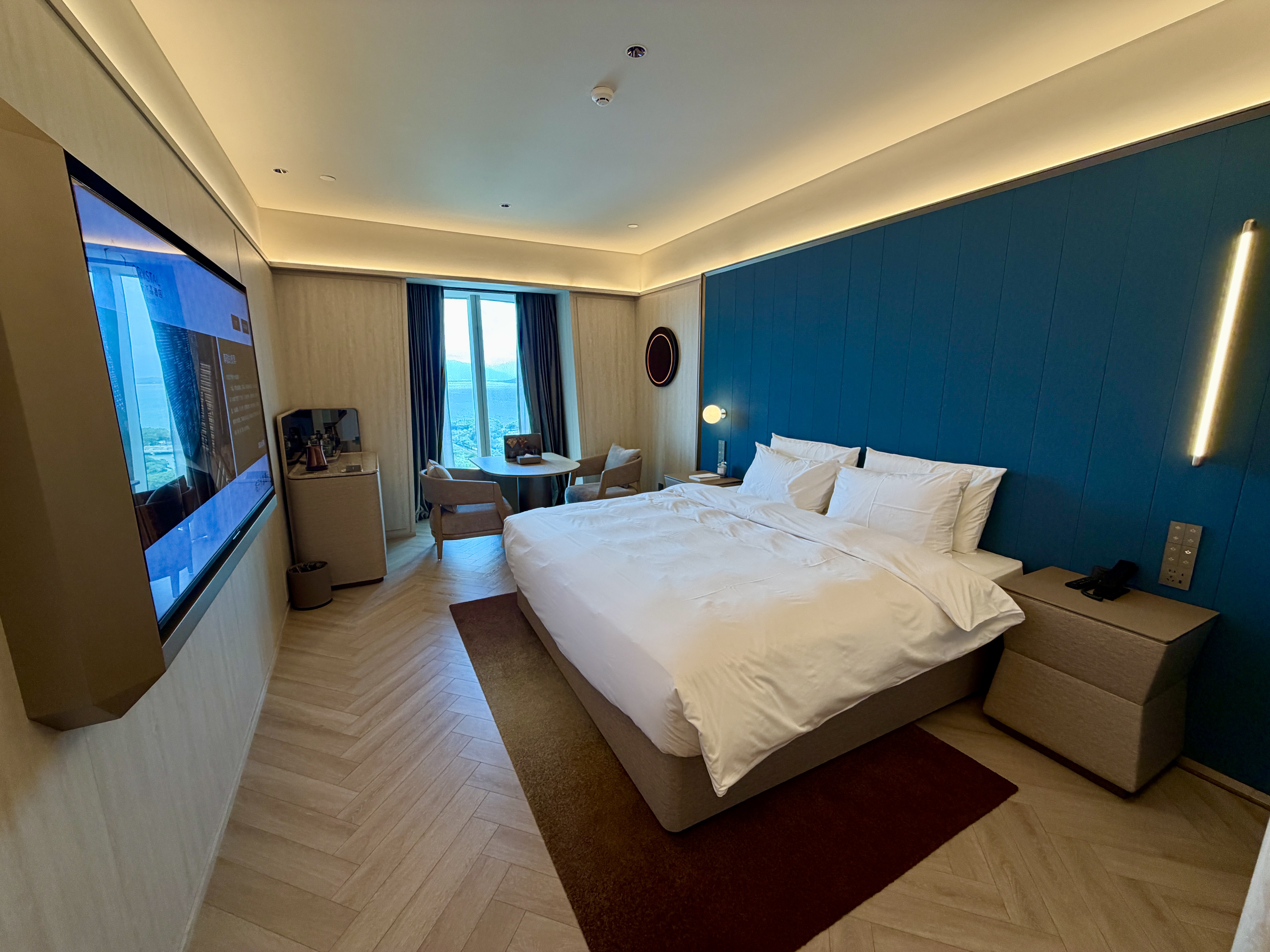 Crystal Orange Shenzhen Bay – Guest room overview with king bed, teal feature wall, and city-view desk