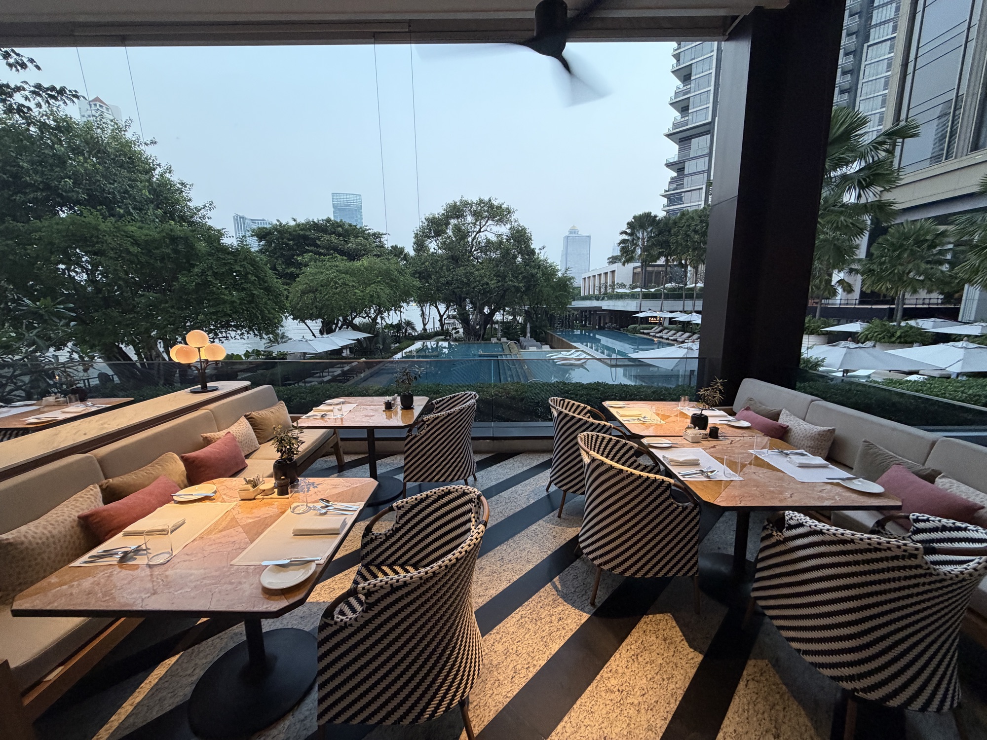 Indoor-outdoor tables open to the garden and river. at Four Seasons Hotel Bangkok at Chao Phraya River