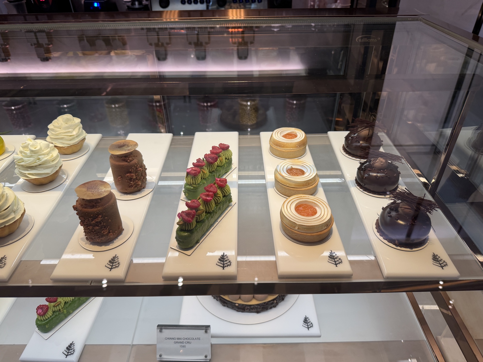 Matcha, chocolate, and citrus entremets in the display case at Café Madeleine at Four Seasons Hotel Bangkok at Chao Phraya River