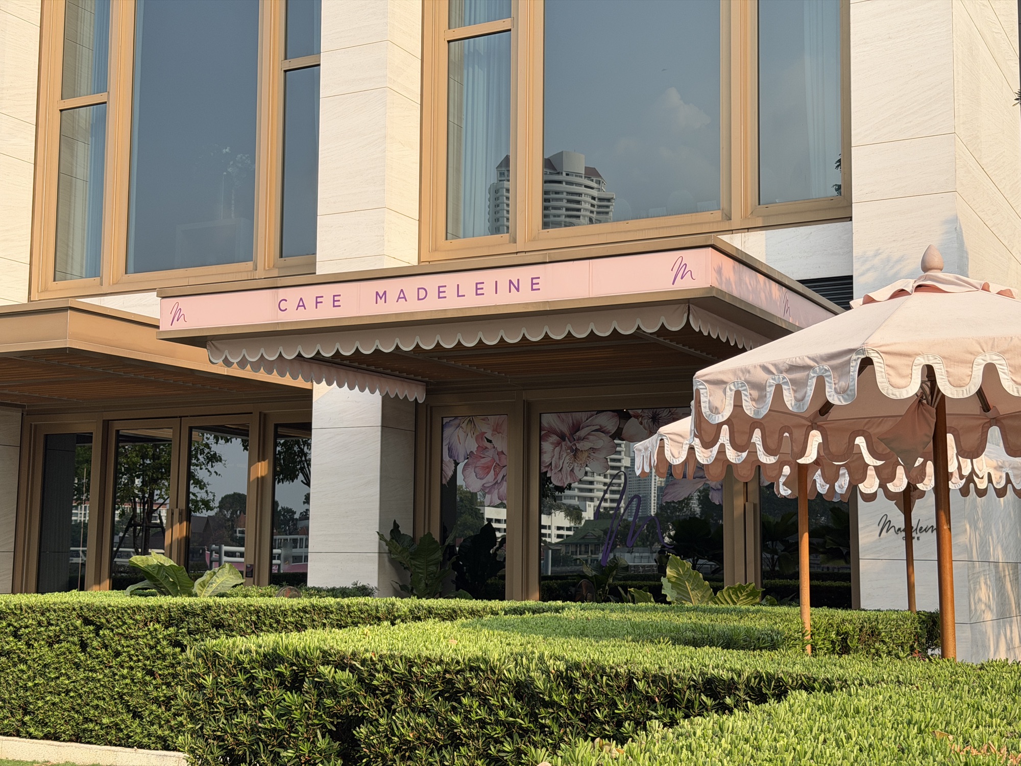 Pink Café Madeleine storefront with scalloped awning and garden at Four Seasons Hotel Bangkok at Chao Phraya River