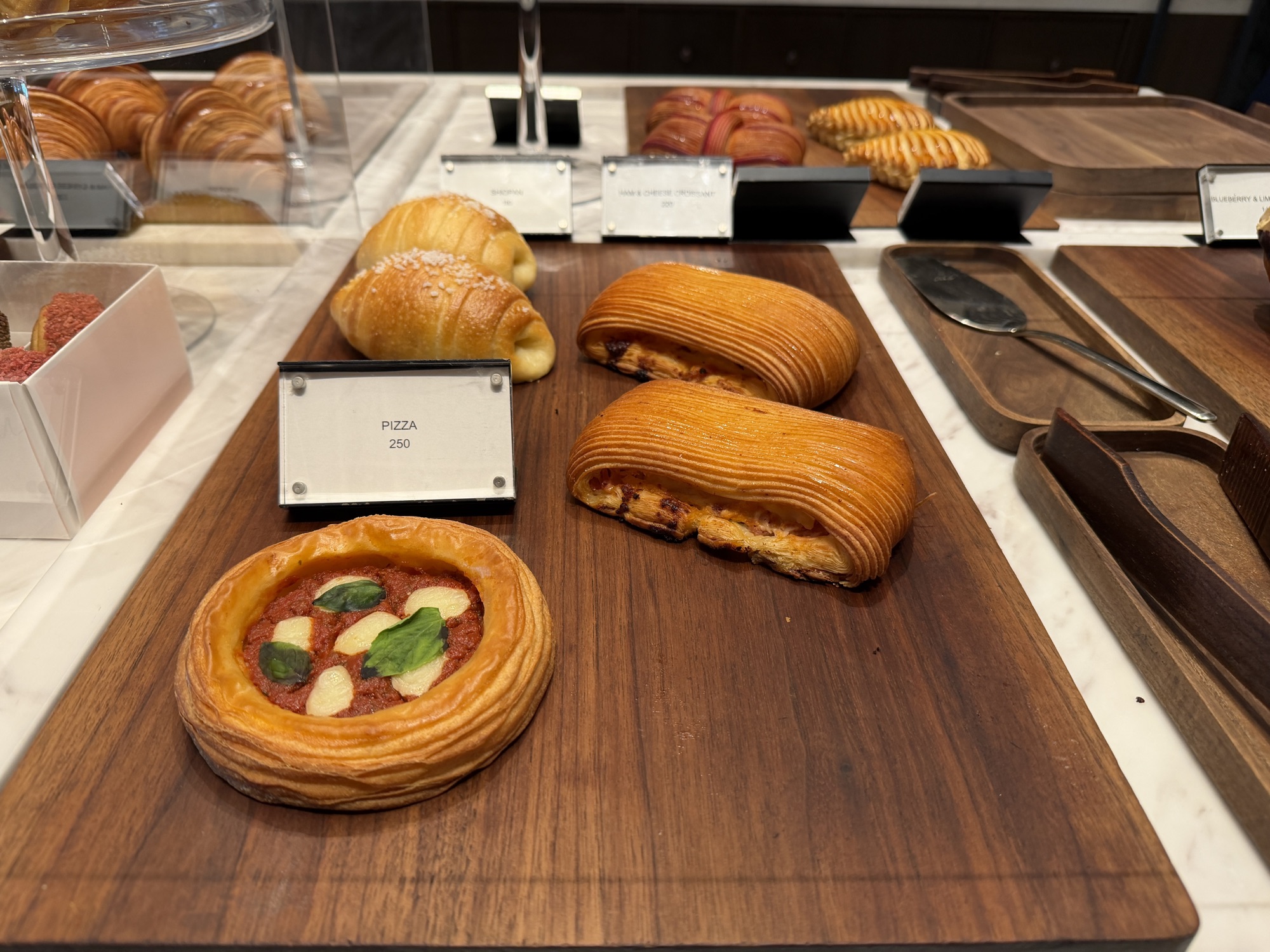 Savoury pastries and viennoiserie on a wood board at Café Madeleine at Four Seasons Hotel Bangkok at Chao Phraya River