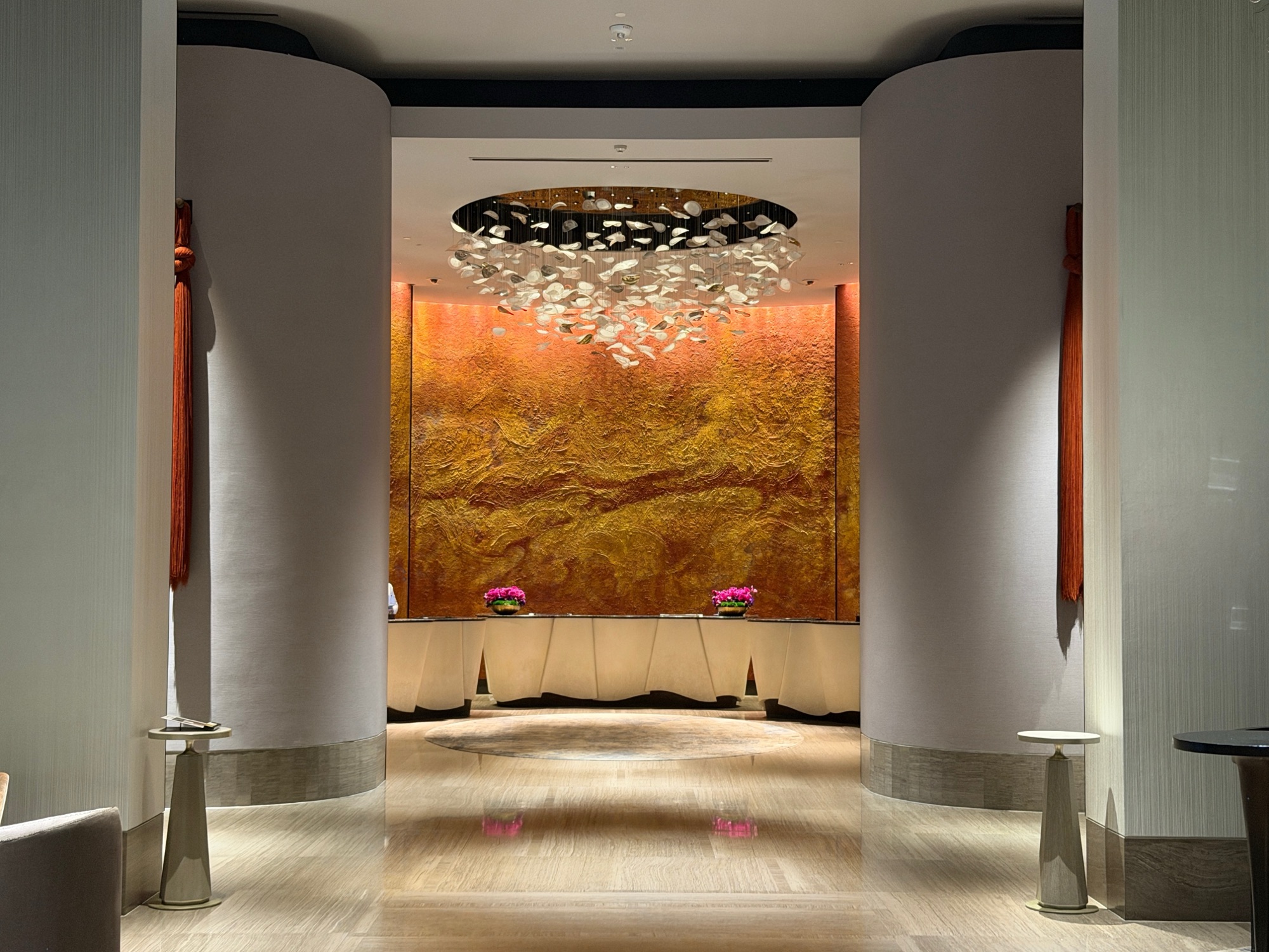 Reception desk beneath a shell chandelier and hand-textured gold-leaf wall at Four Seasons Hotel Bangkok at Chao Phraya River