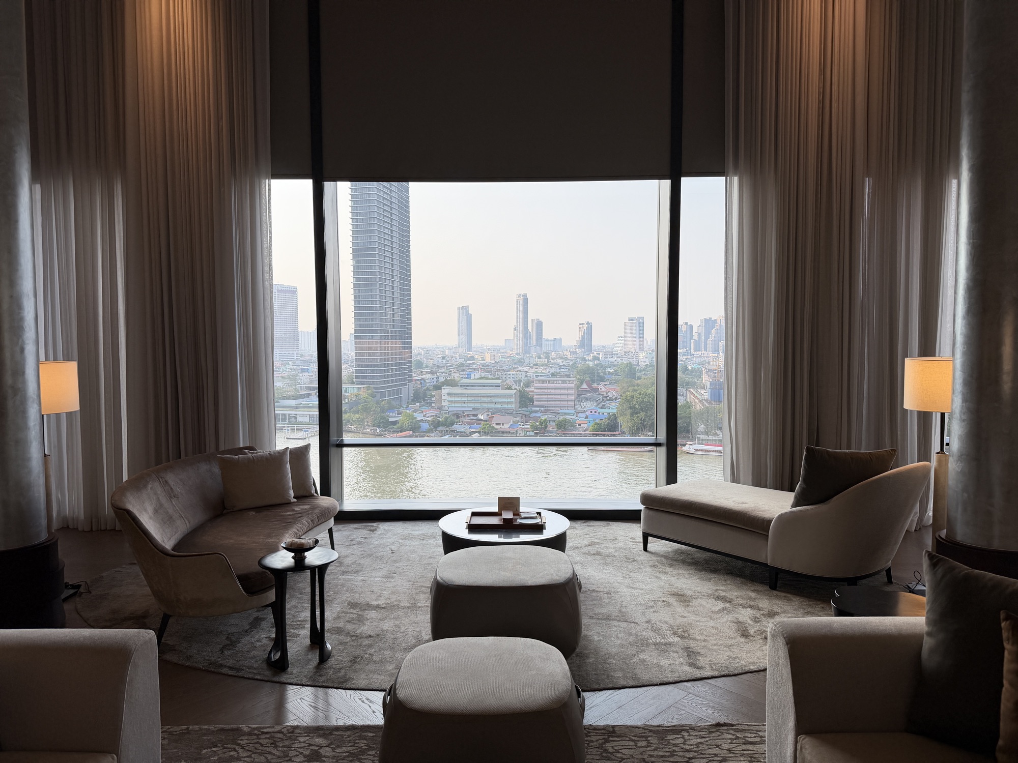 River-facing lounge framed by floor-to-ceiling glass in the Riverfront Penthouse at Four Seasons Hotel Bangkok at Chao Phraya River