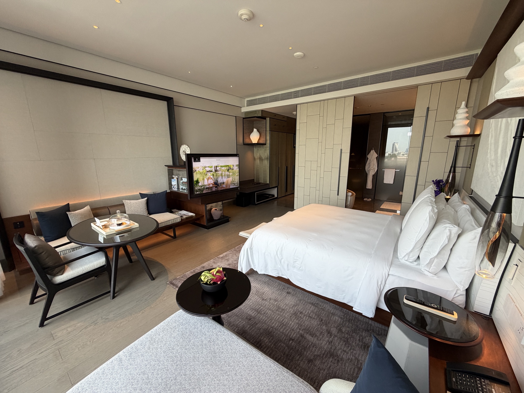 Deluxe River-View Room showing the bed, TV console, sitting area, and bathroom beyond at Four Seasons Hotel Bangkok at Chao Phraya River