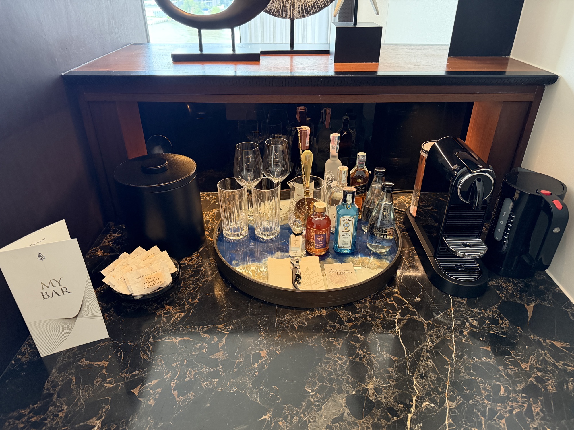 My Bar setup with glassware, spirits, and a Nespresso machine in the Deluxe River-View Room at Four Seasons Hotel Bangkok at Chao Phraya River