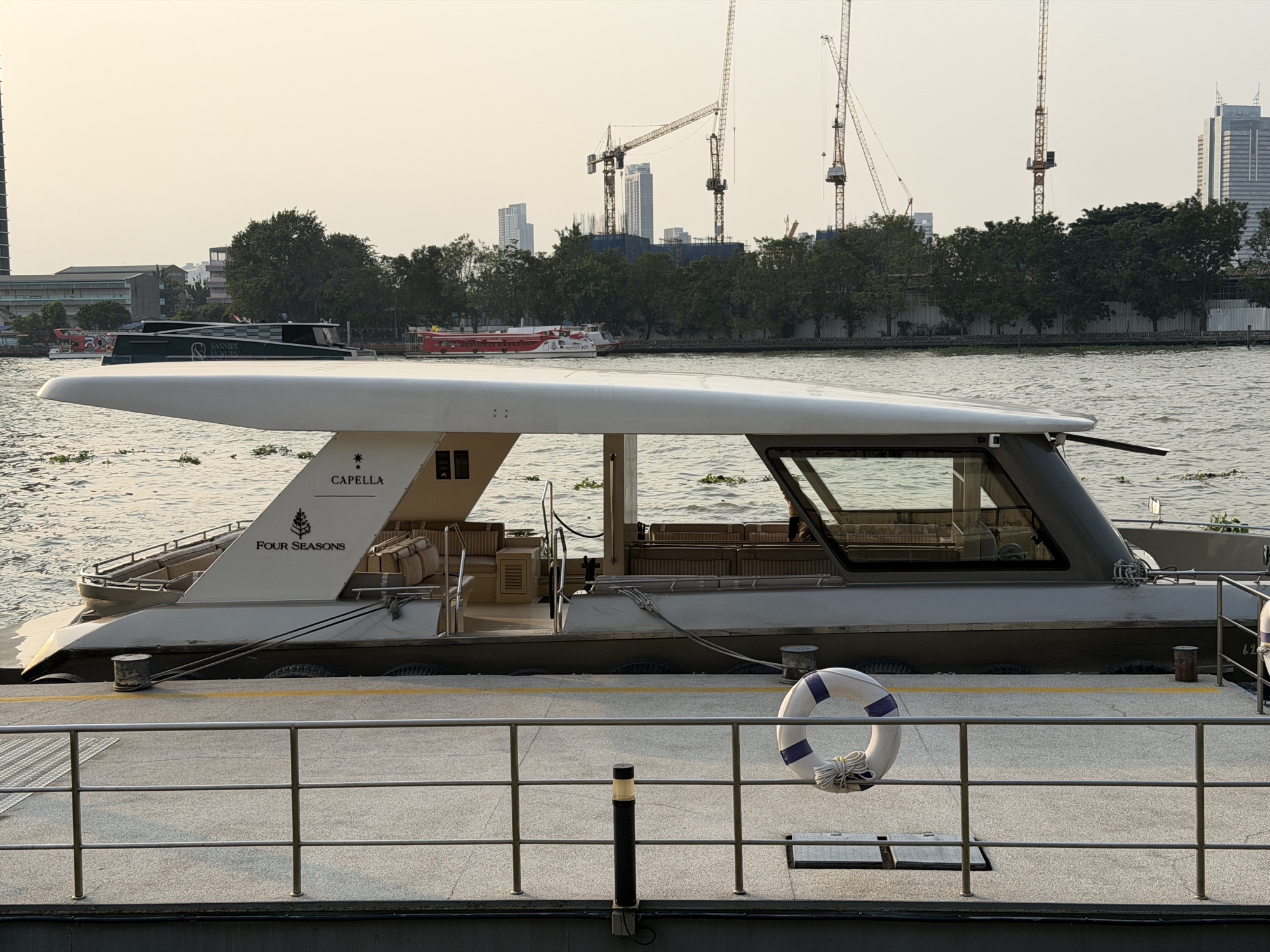 Chao Phraya Estate shuttle boat with Capella and Four Seasons crests docked at the pier at Four Seasons Hotel Bangkok at Chao Phraya River