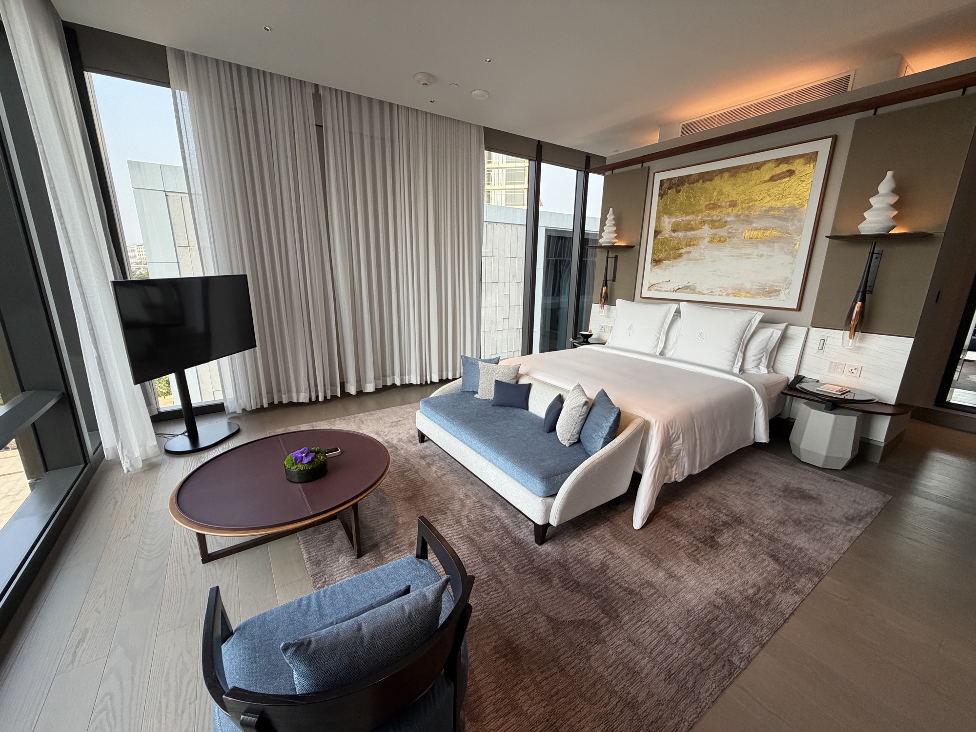 Wide angle of the Executive Suite bedroom with TV and sitting bench at Four Seasons Hotel Bangkok at Chao Phraya River