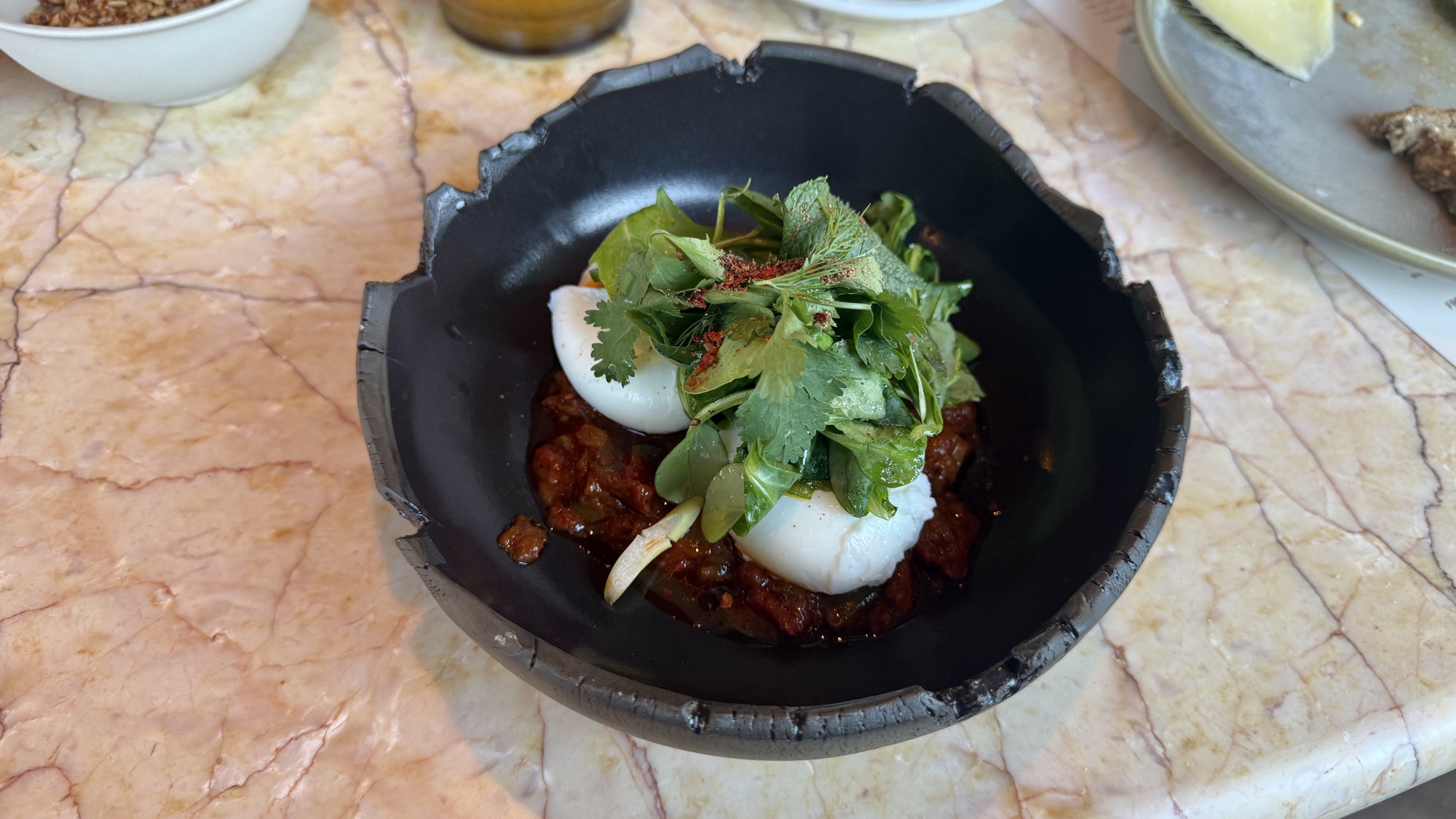 À la carte egg dish plated in a black bowl with herbs