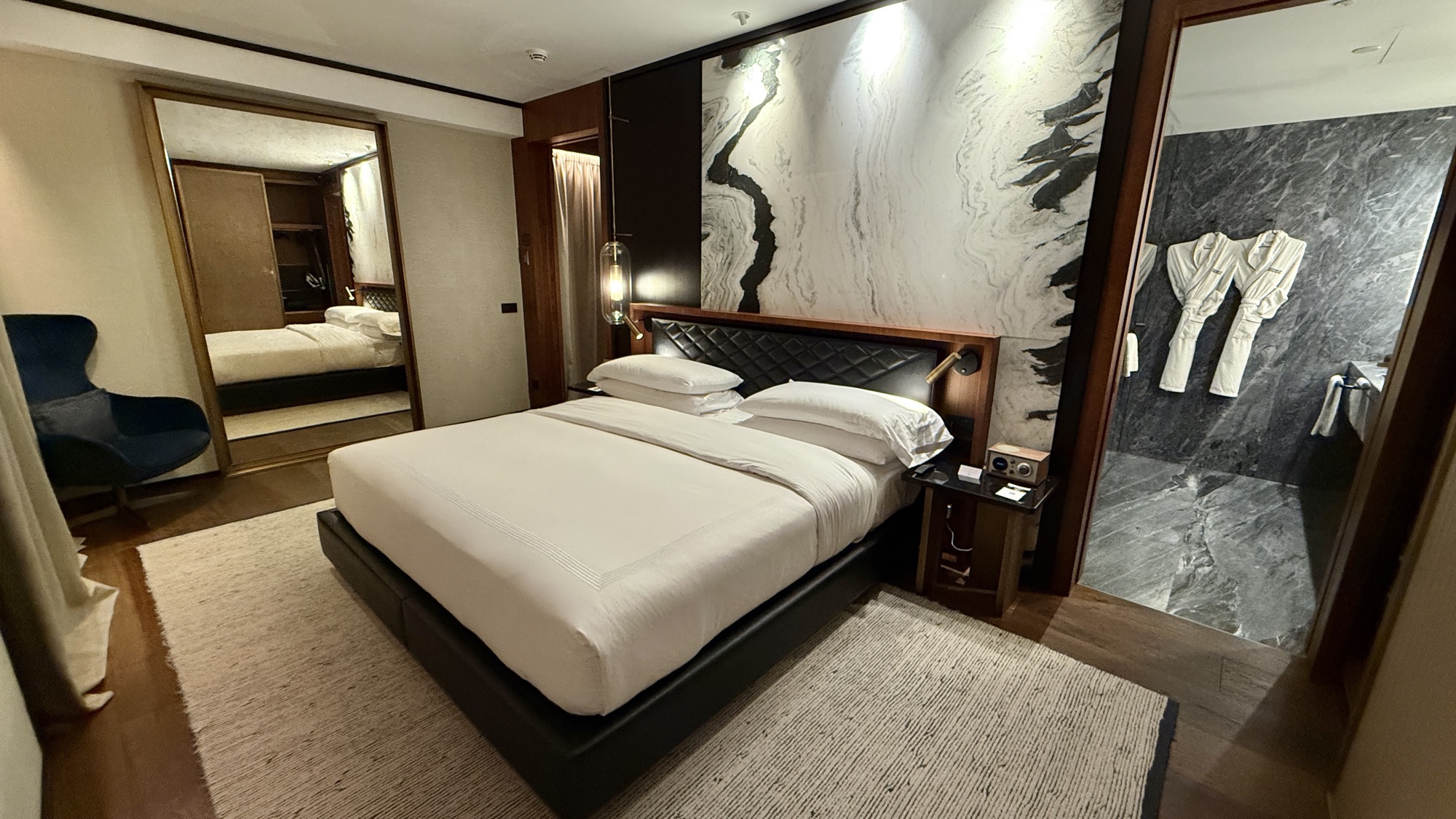 Corner Suite bedroom with a floor-to-ceiling mirror reflecting a blue armchair