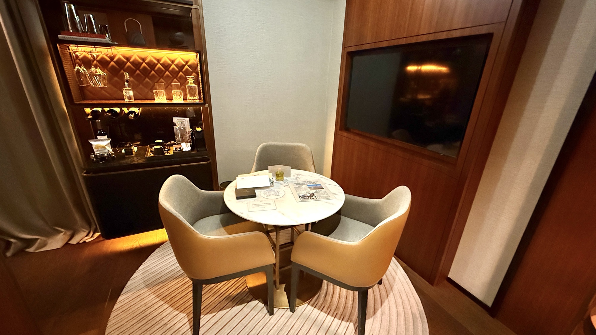 Corner Suite seating nook with a round marble table and illuminated minibar cabinet