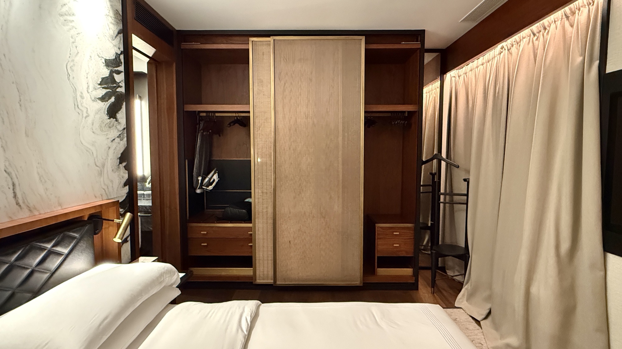Corner Suite bedroom with an open wardrobe behind wooden panels