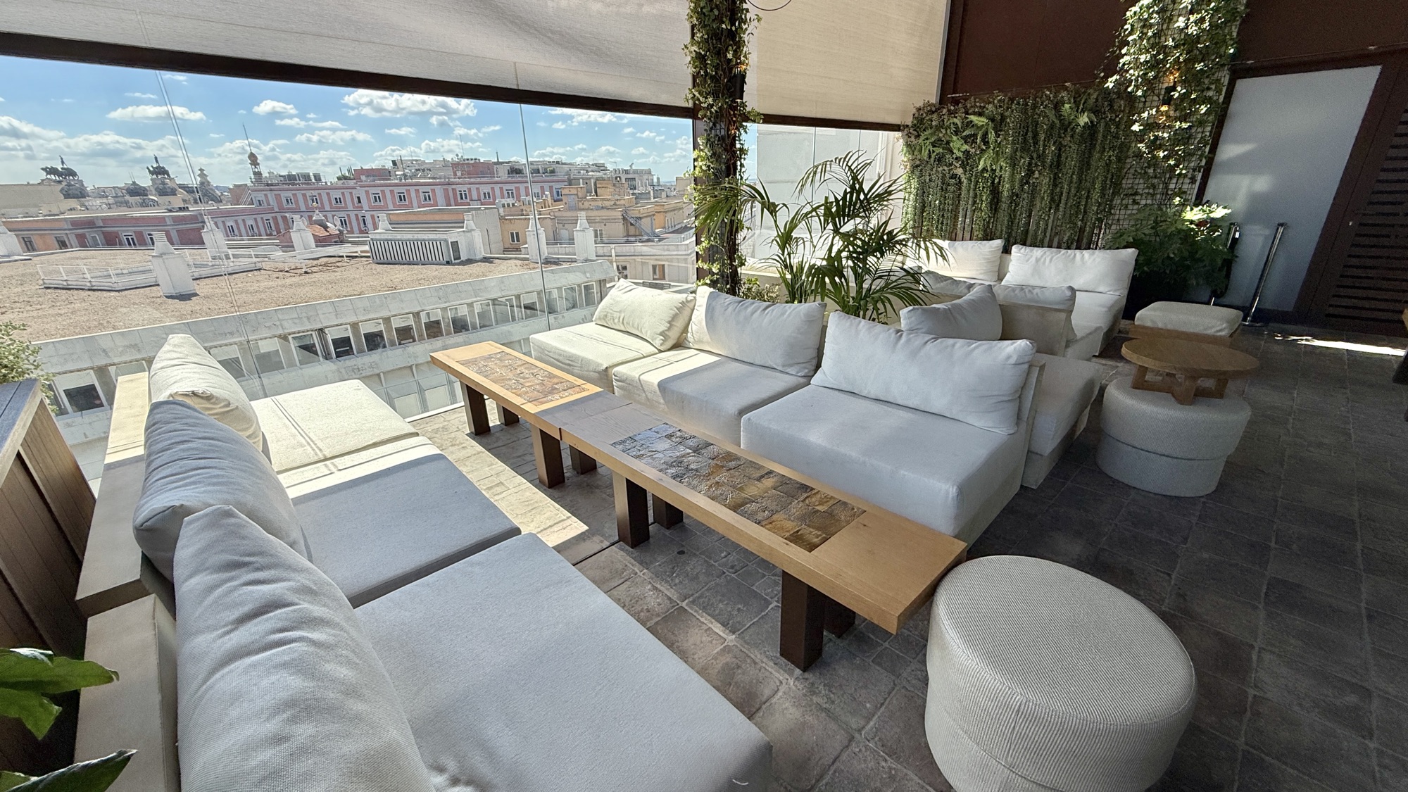 Rooftop lounge with white sofas and wood tables overlooking central Madrid