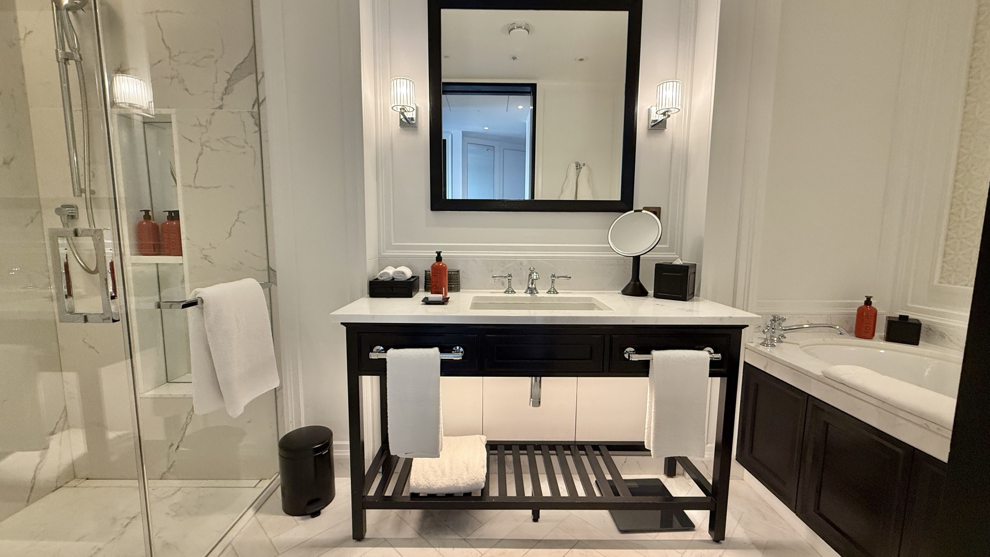 Marble bathroom with walk-in rain shower, dark wood vanity, and deep soaking tub