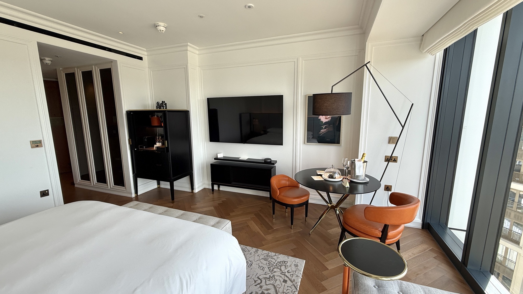 Wider view of the River View room showing the bed, seating, television, and floor lamp