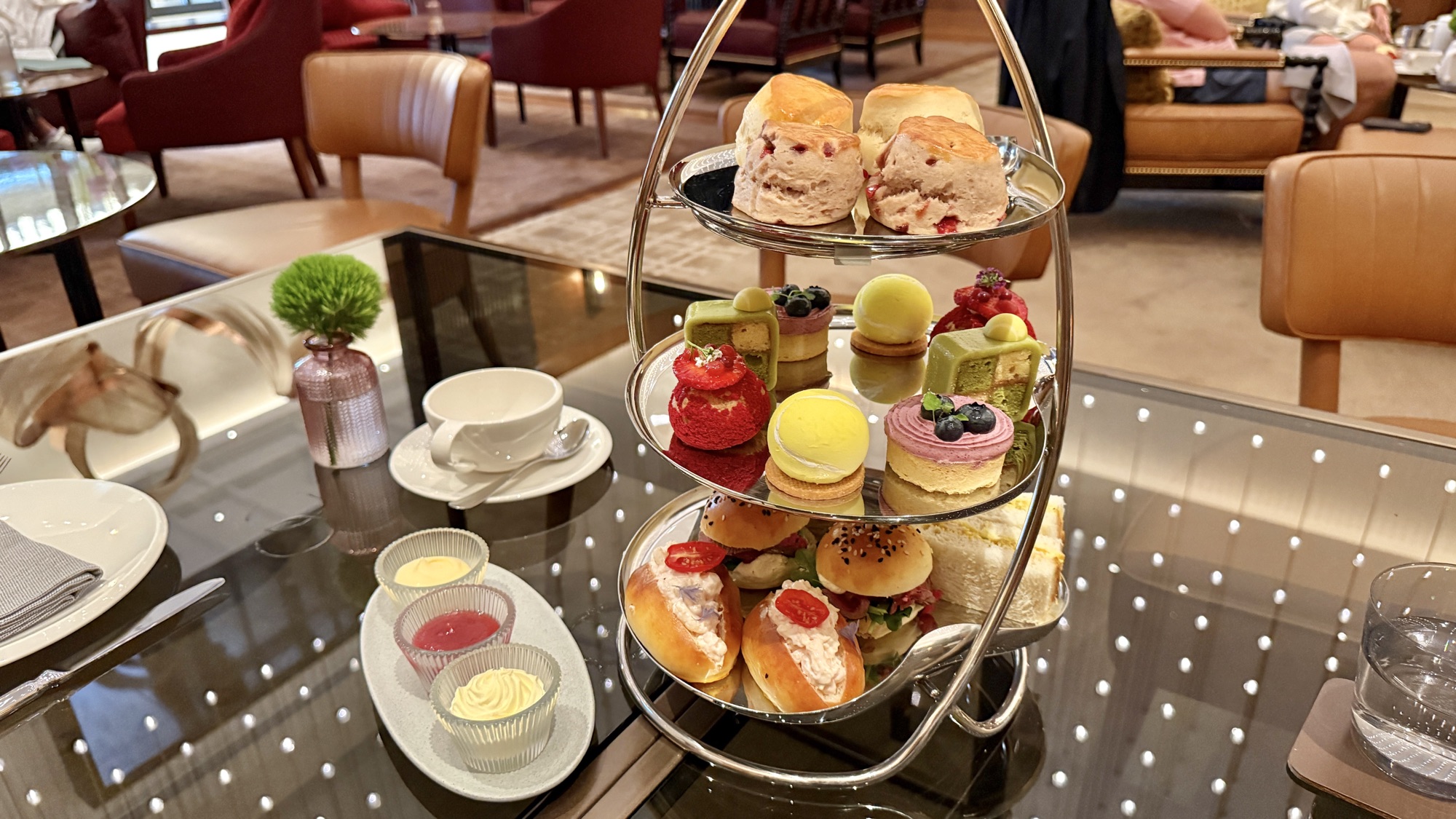 Three-tier afternoon tea stand with scones, finger sandwiches, macarons, and pastries