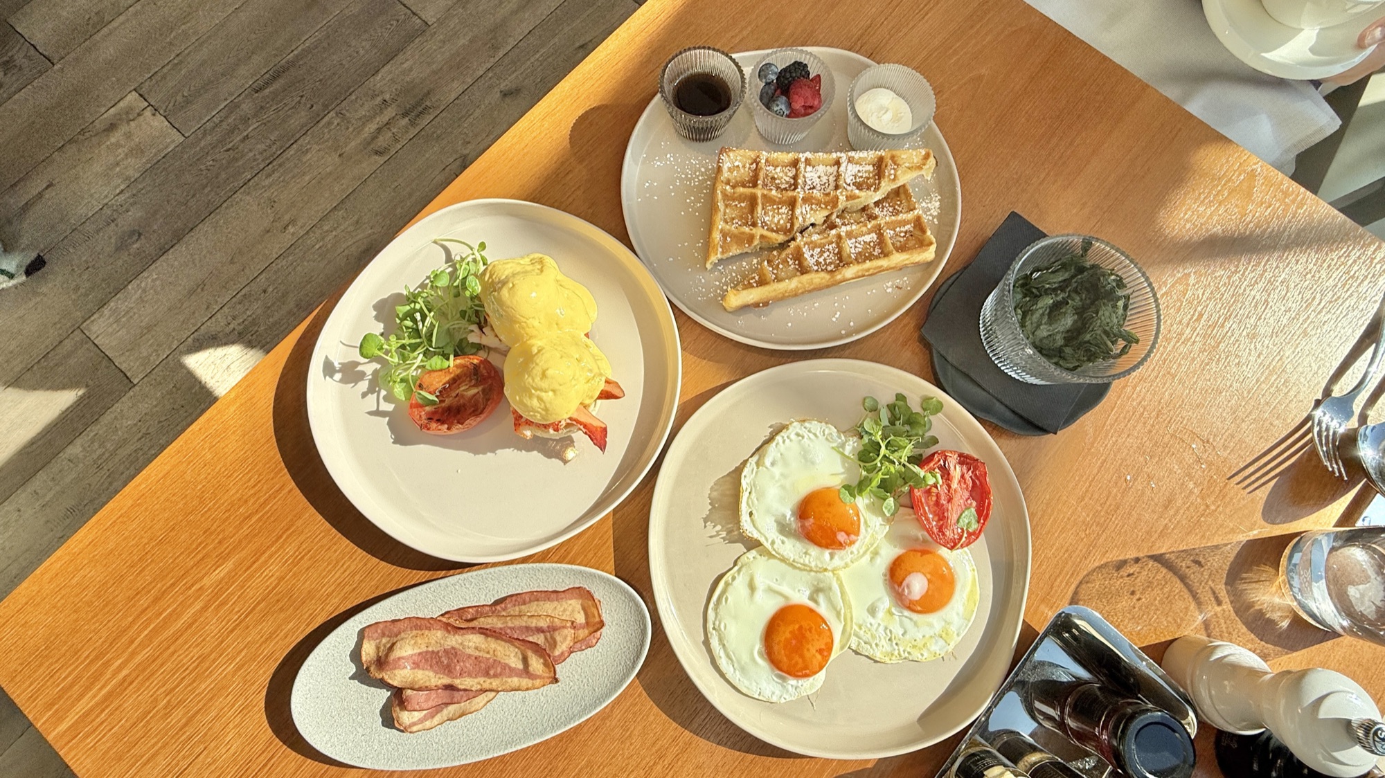 A la carte breakfast of eggs benedict, waffles with berries, and fried eggs with bacon