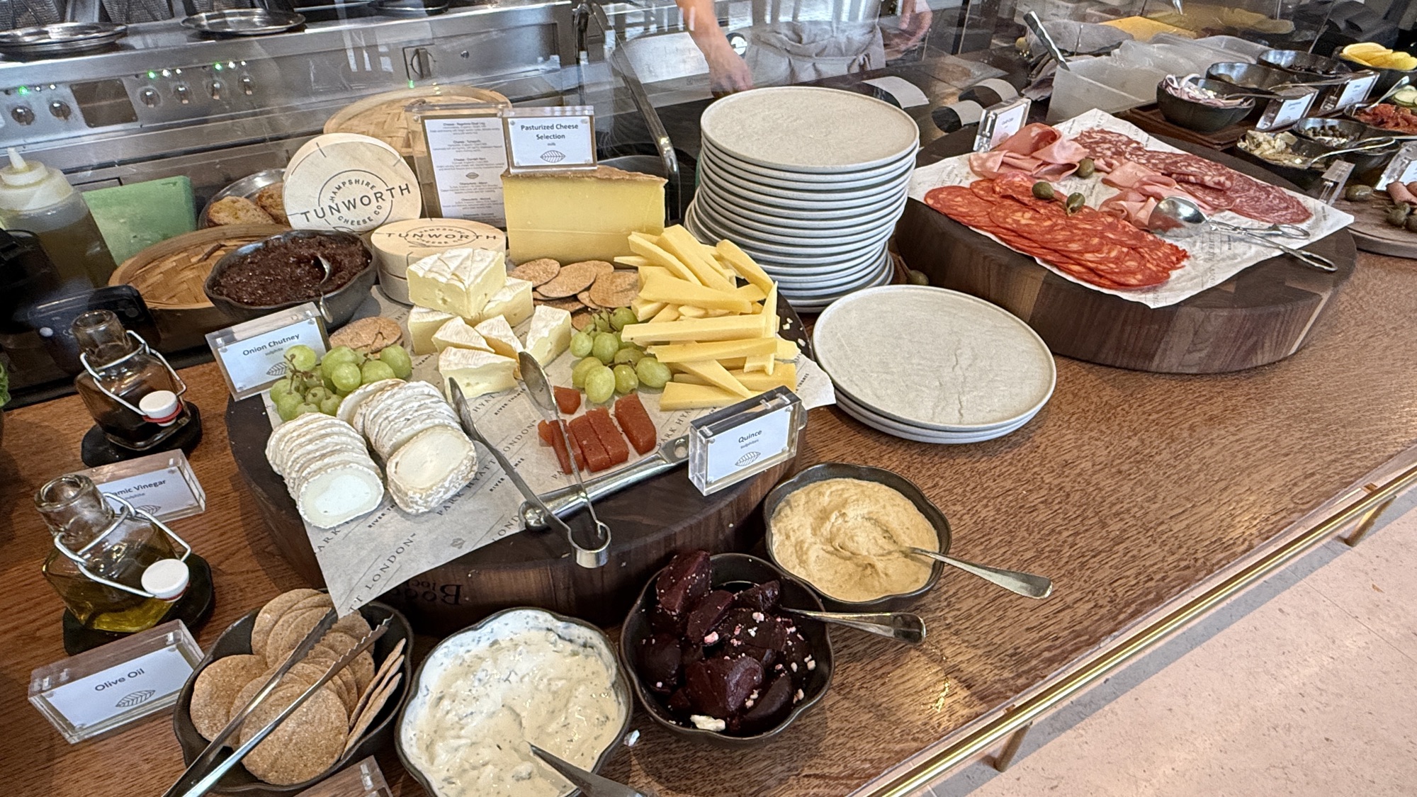 Cheese and charcuterie station with cured meats, cheeses, grapes, and spreads at breakfast