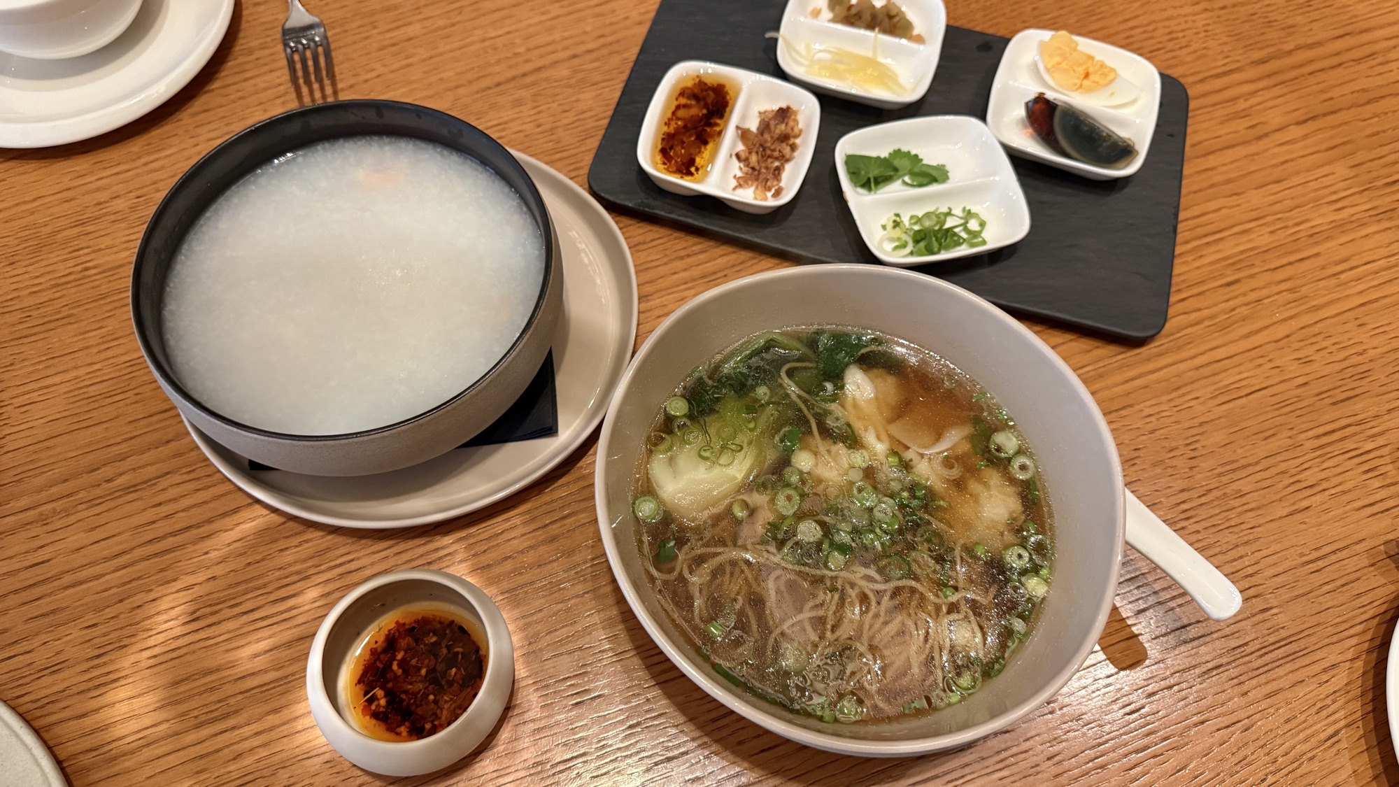 A la carte congee and wonton noodle soup from the Asian breakfast menu with condiments
