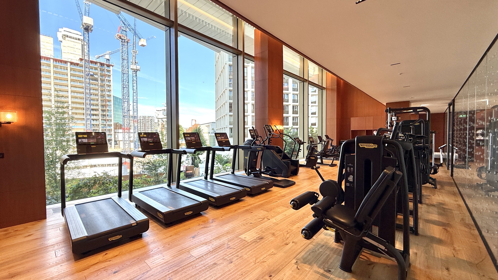 Fitness centre with treadmills and weight machines beside floor-to-ceiling windows