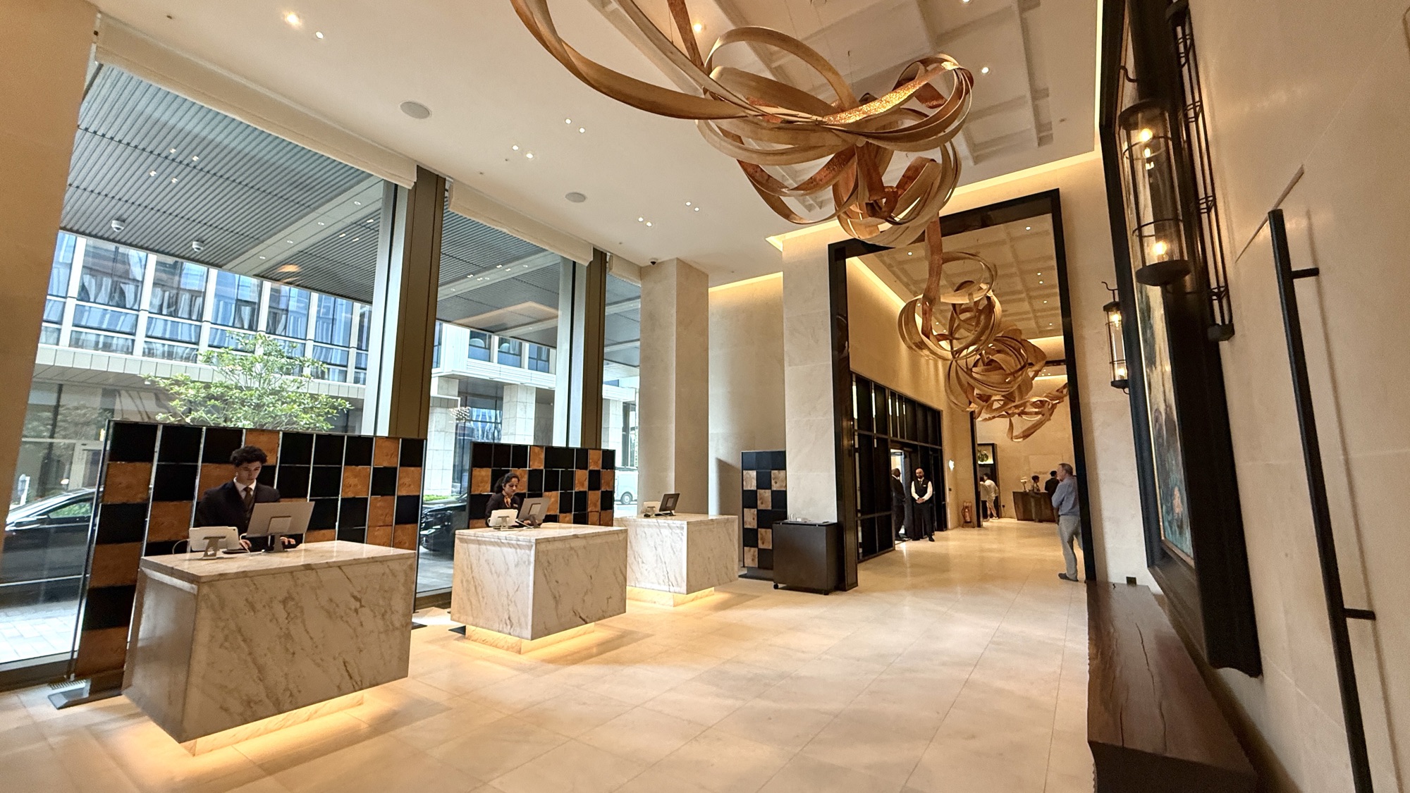 Reception desks in the Park Hyatt London River Thames lobby beneath the copper Ebb and Flow ribbon sculpture