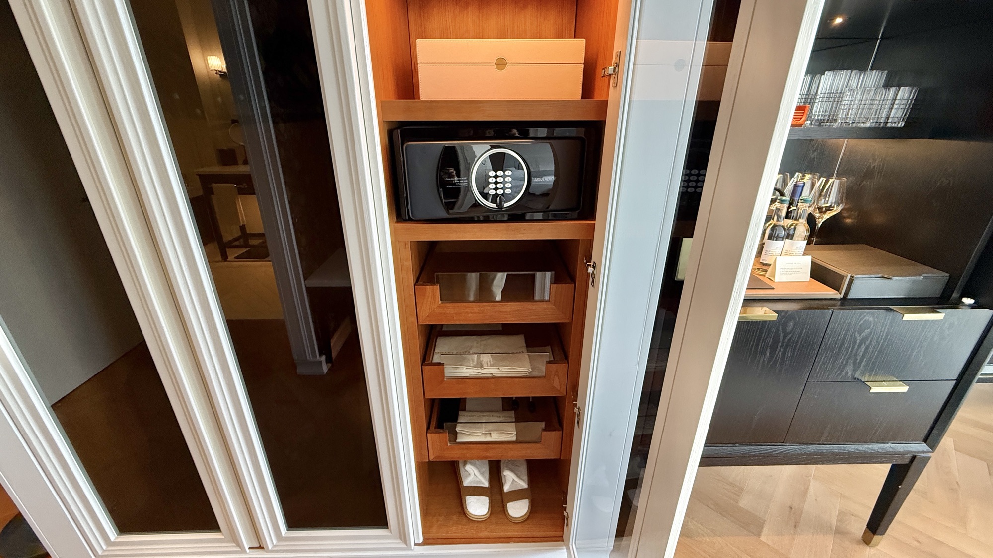 Open wardrobe with in-room safe, slippers, and shelving in the River View room