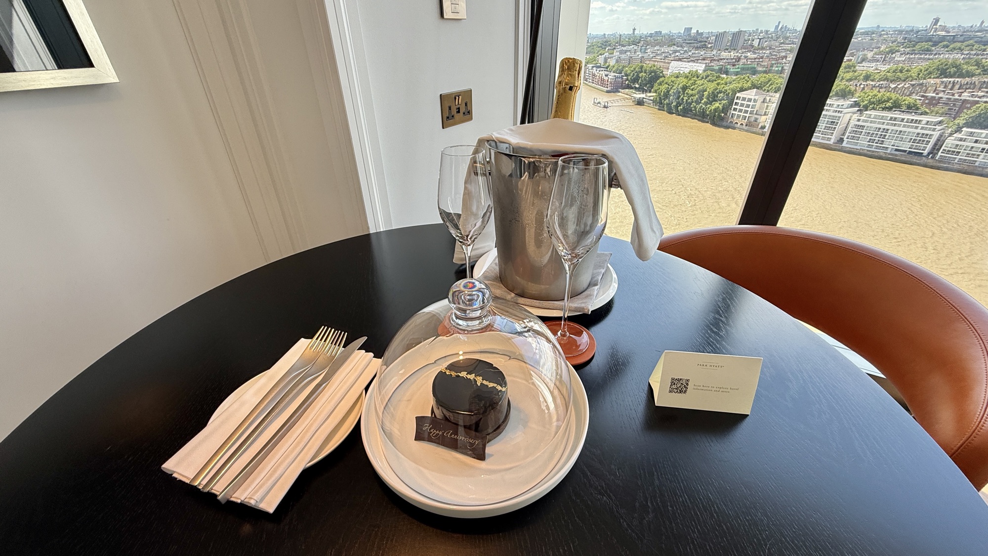 Welcome gift of a small cake under a glass cloche with a handwritten card on the room's table