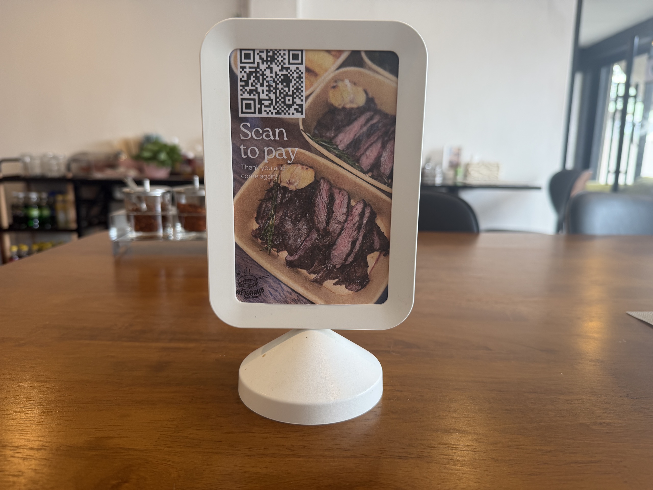 A scan-to-pay QR code stand on a restaurant table in Thailand