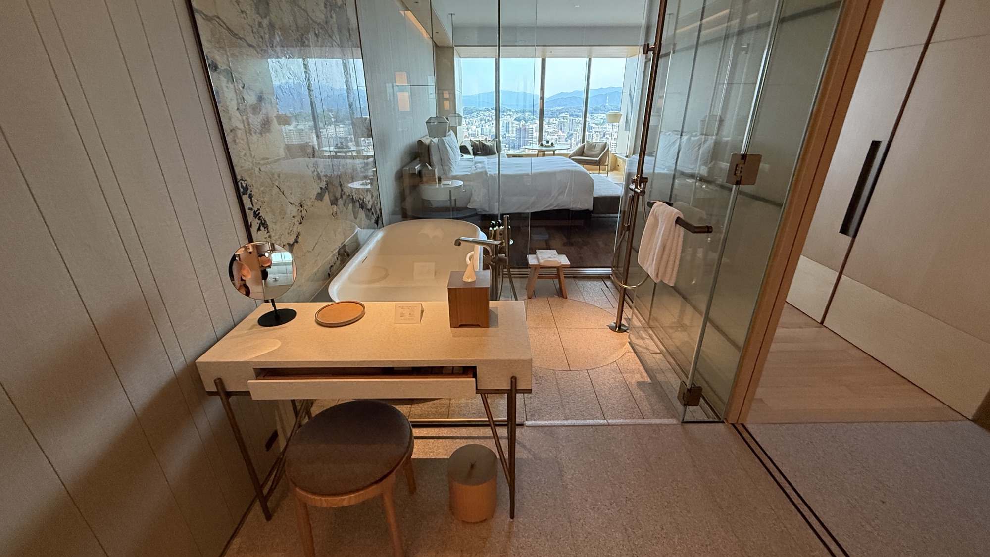 Bathtub, vanity table and glazed panels looking through to the city