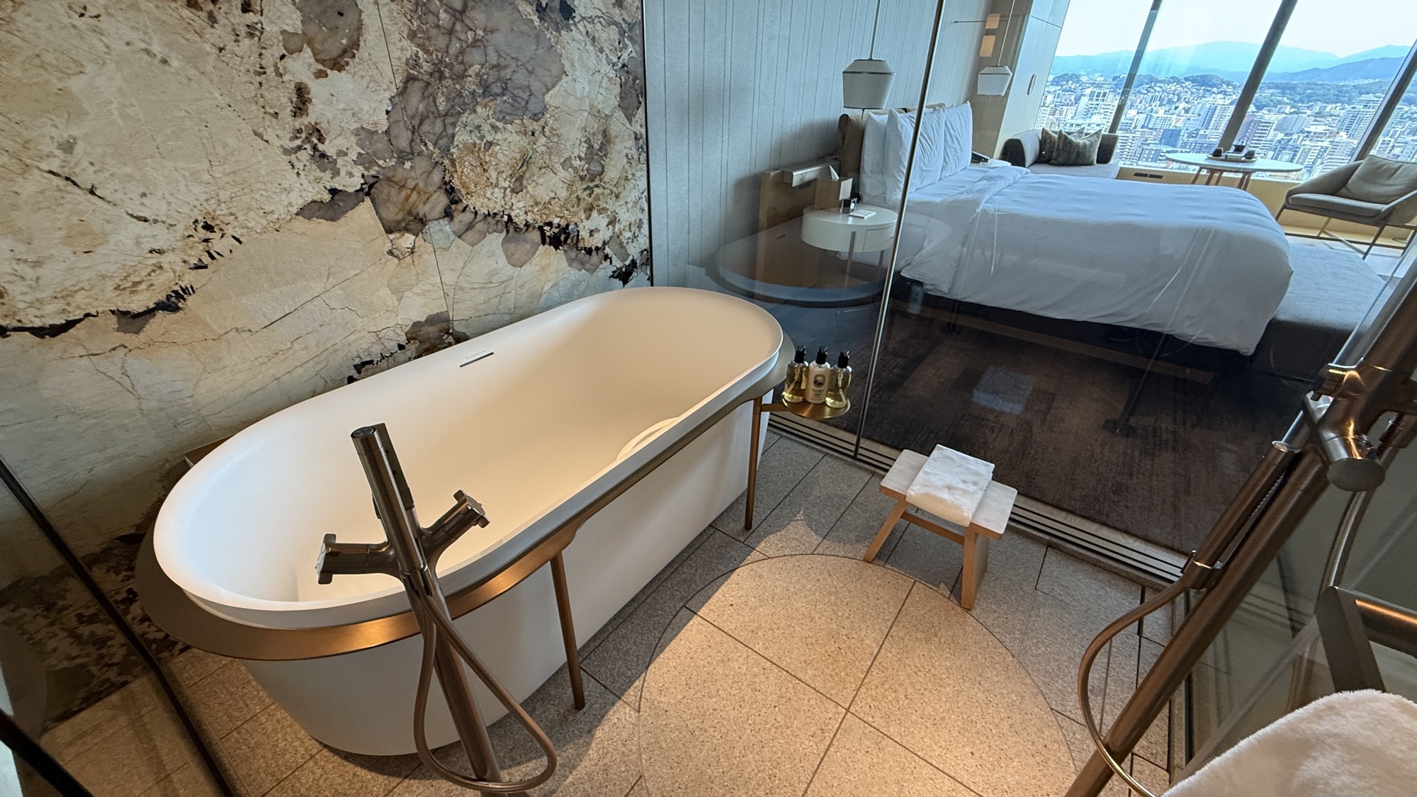 Freestanding oval bathtub against the stone feature wall
