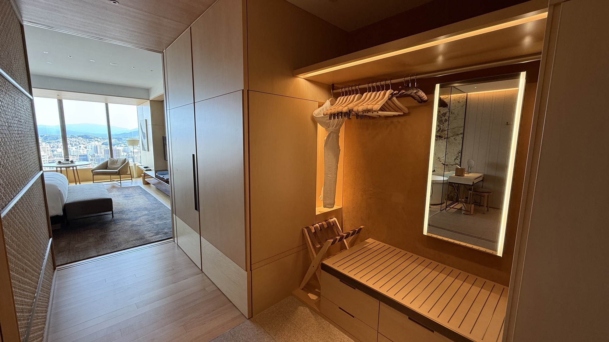Dressing area with lit mirror, hanging rail and bench