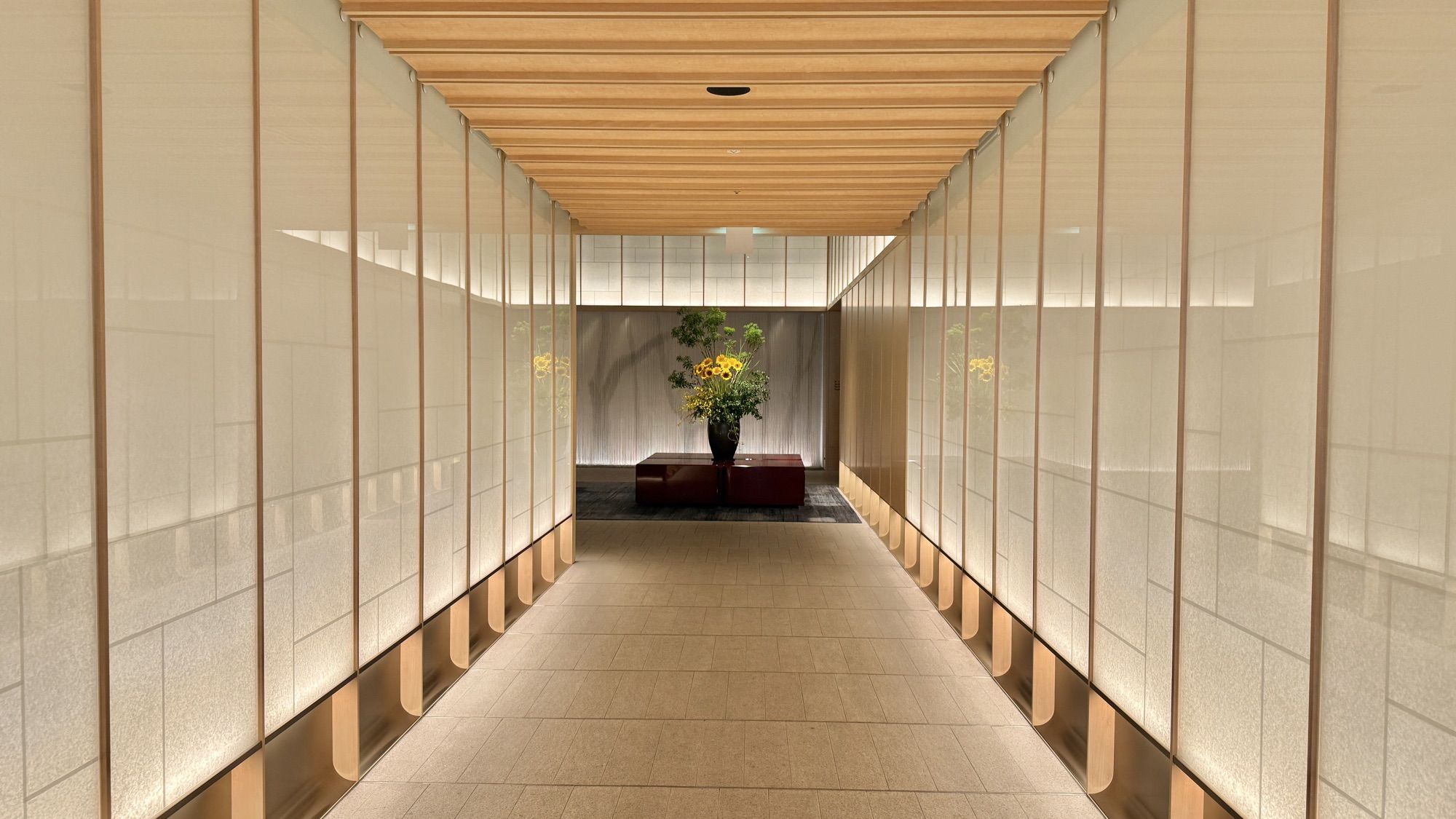 Lit arrival corridor lined with translucent screen panels leading into the lobby at The Ritz-Carlton, Fukuoka