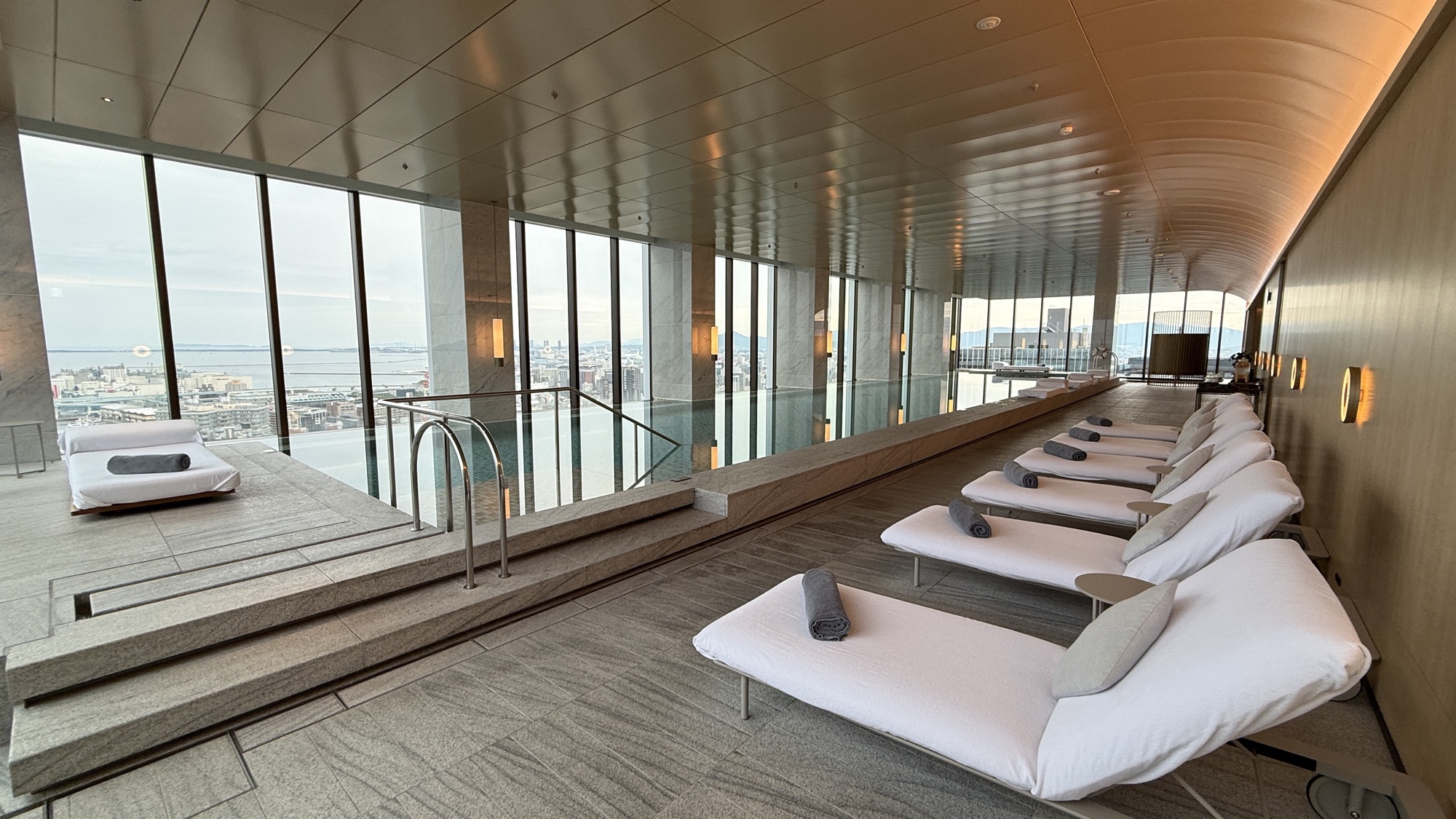 The infinity pool with loungers and floor to ceiling windows over the city