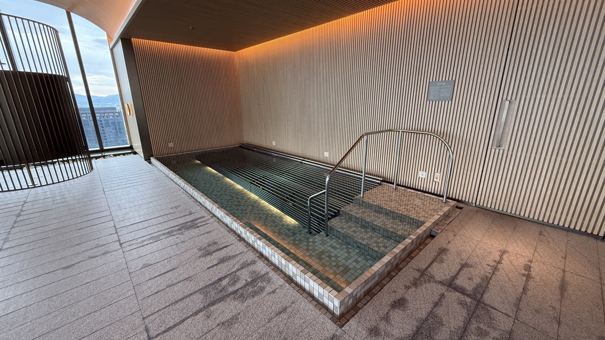 Sunken pool with tiled surround beside the window