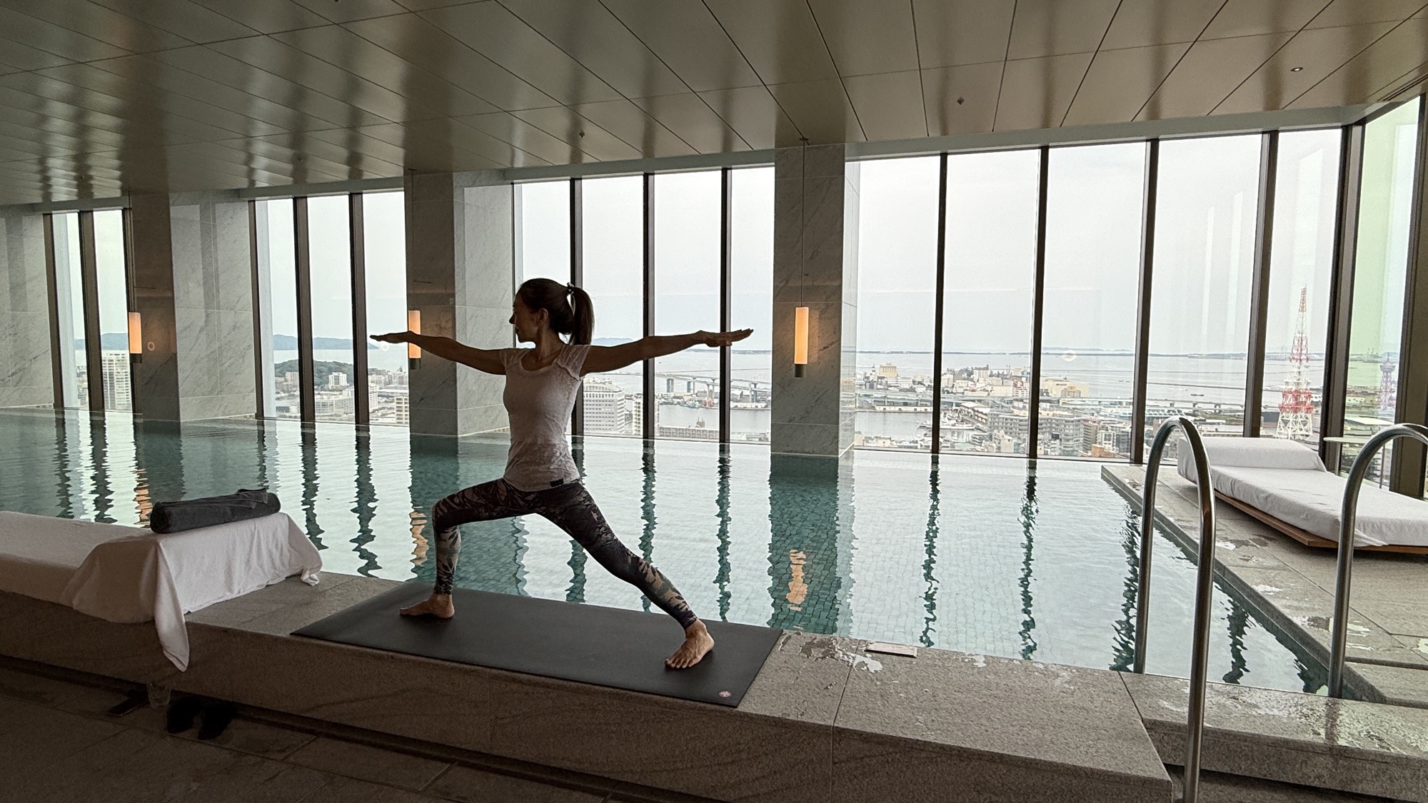 A guest practising yoga on a mat beside the infinity pool