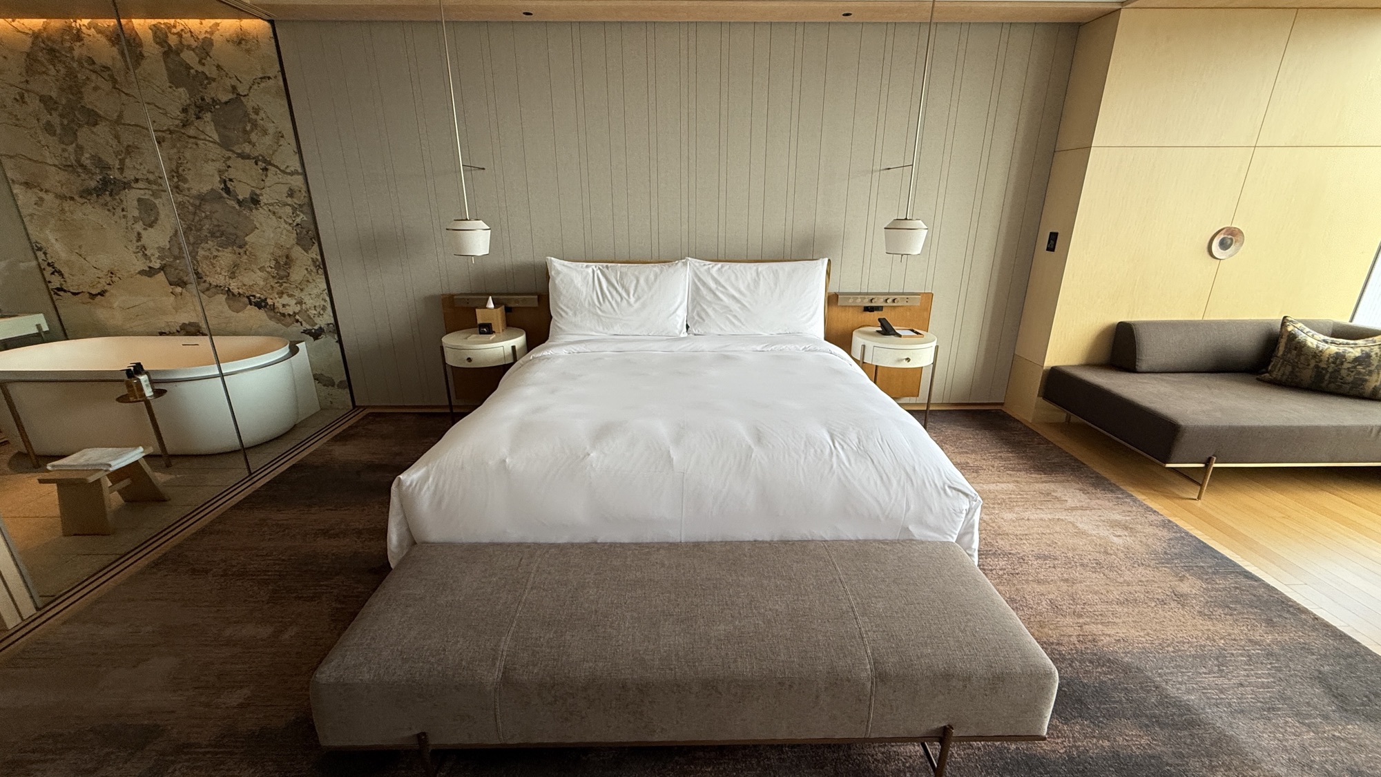 King bed with bench, bedside tables and the bathroom glazing behind