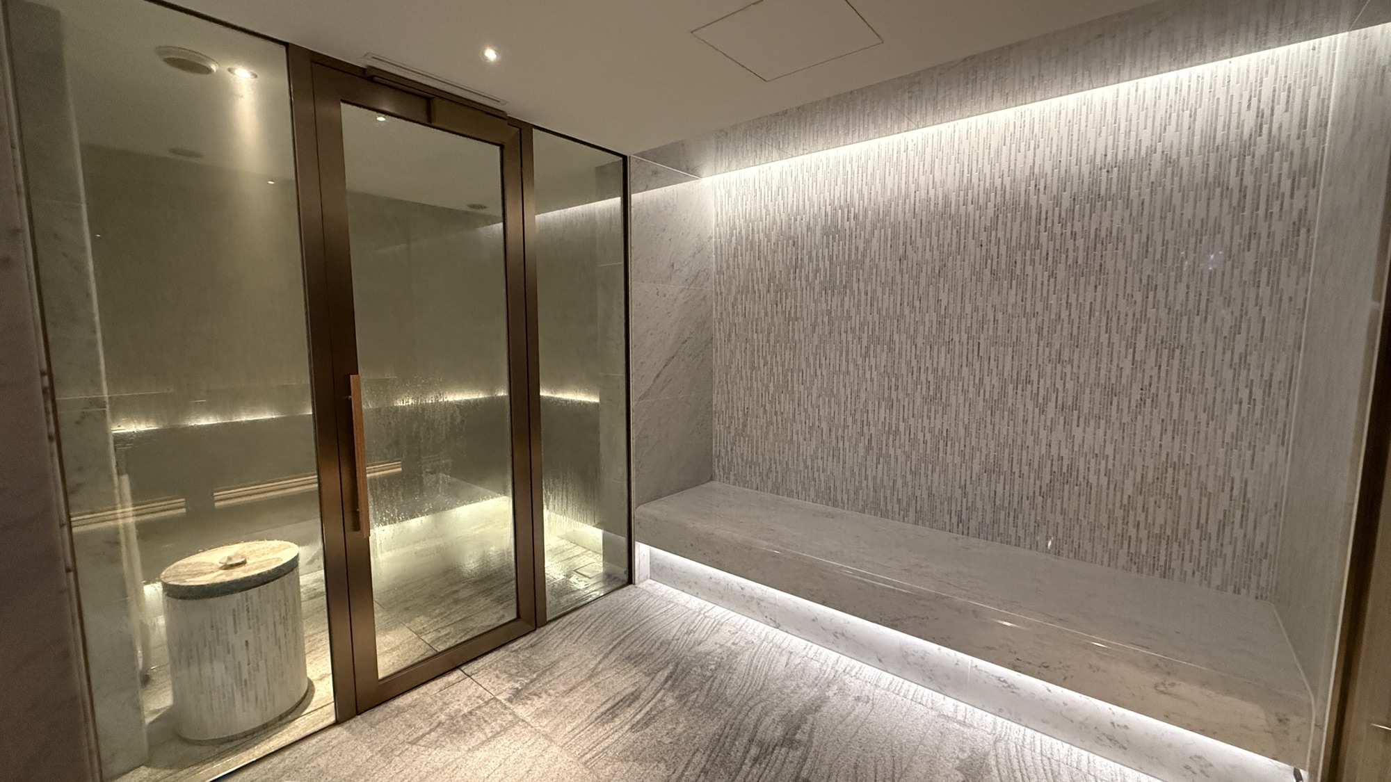 Glass walled steam room with a stone bench