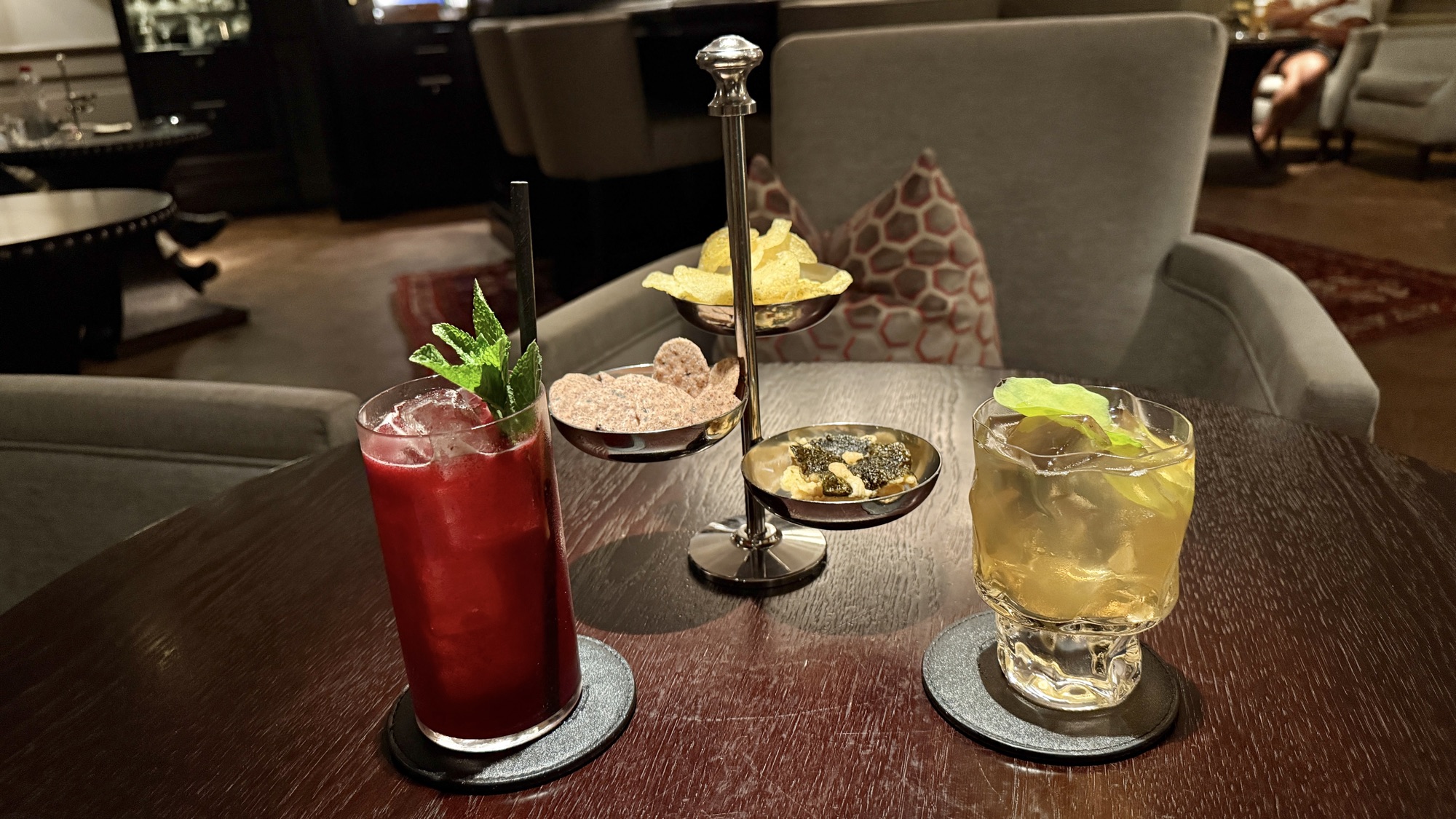 Two cocktails with garnishes and small snacks at the Vault Bar