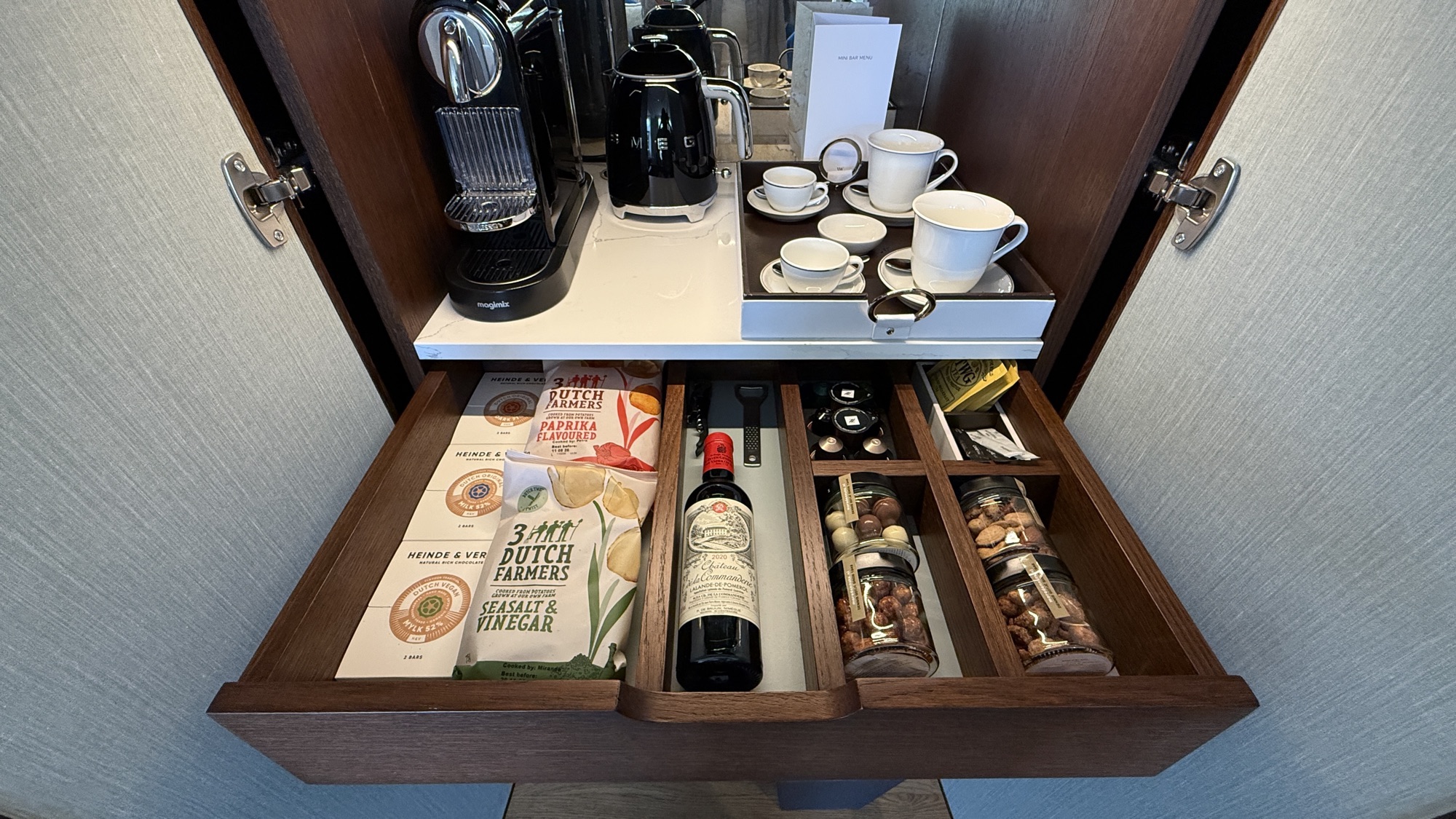 Open drawer with a Nespresso machine, cups, and Dutch snacks in the King Grand Premier room