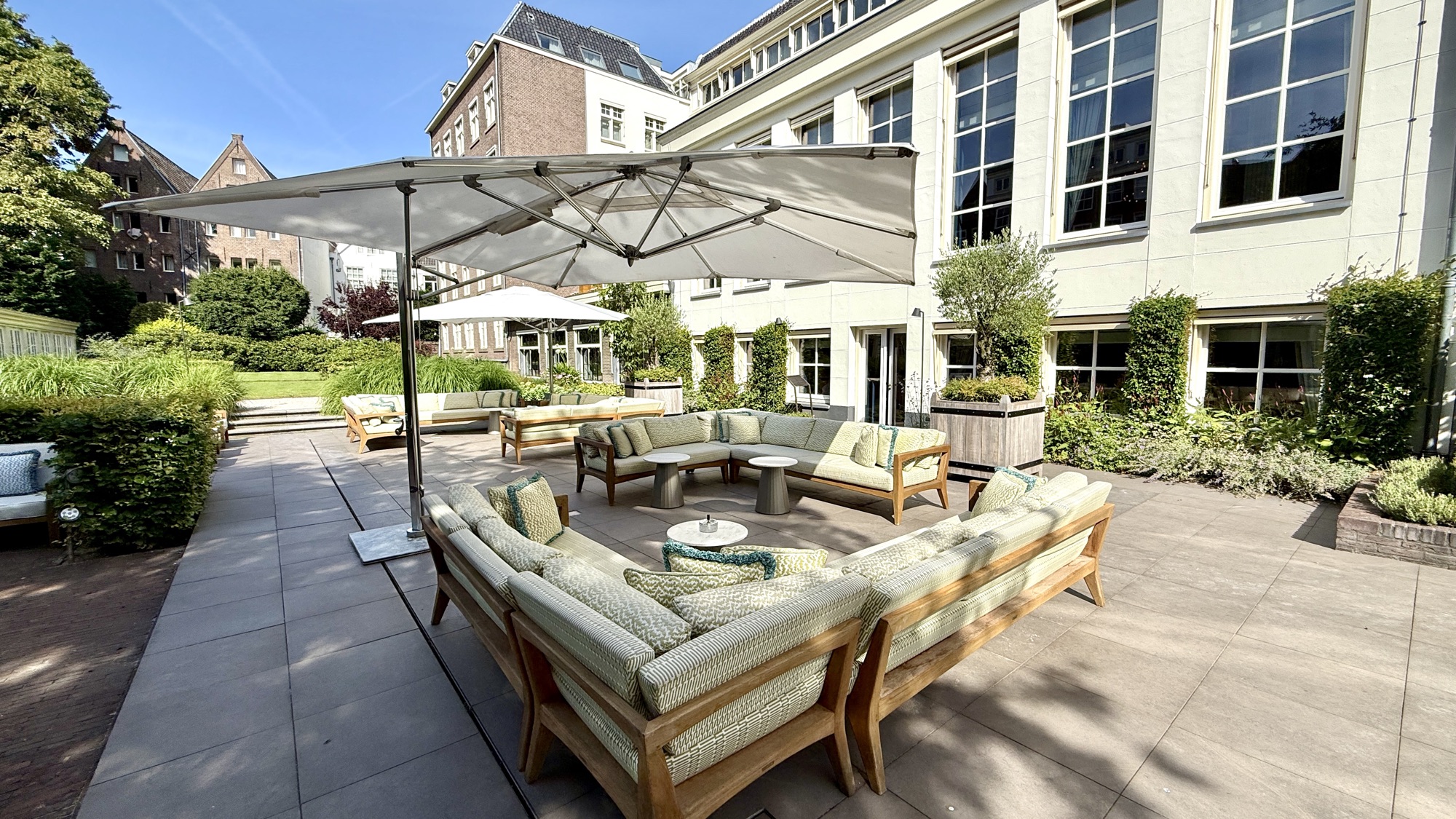 Outdoor courtyard terrace with sofas and a large parasol at the Waldorf Astoria Amsterdam