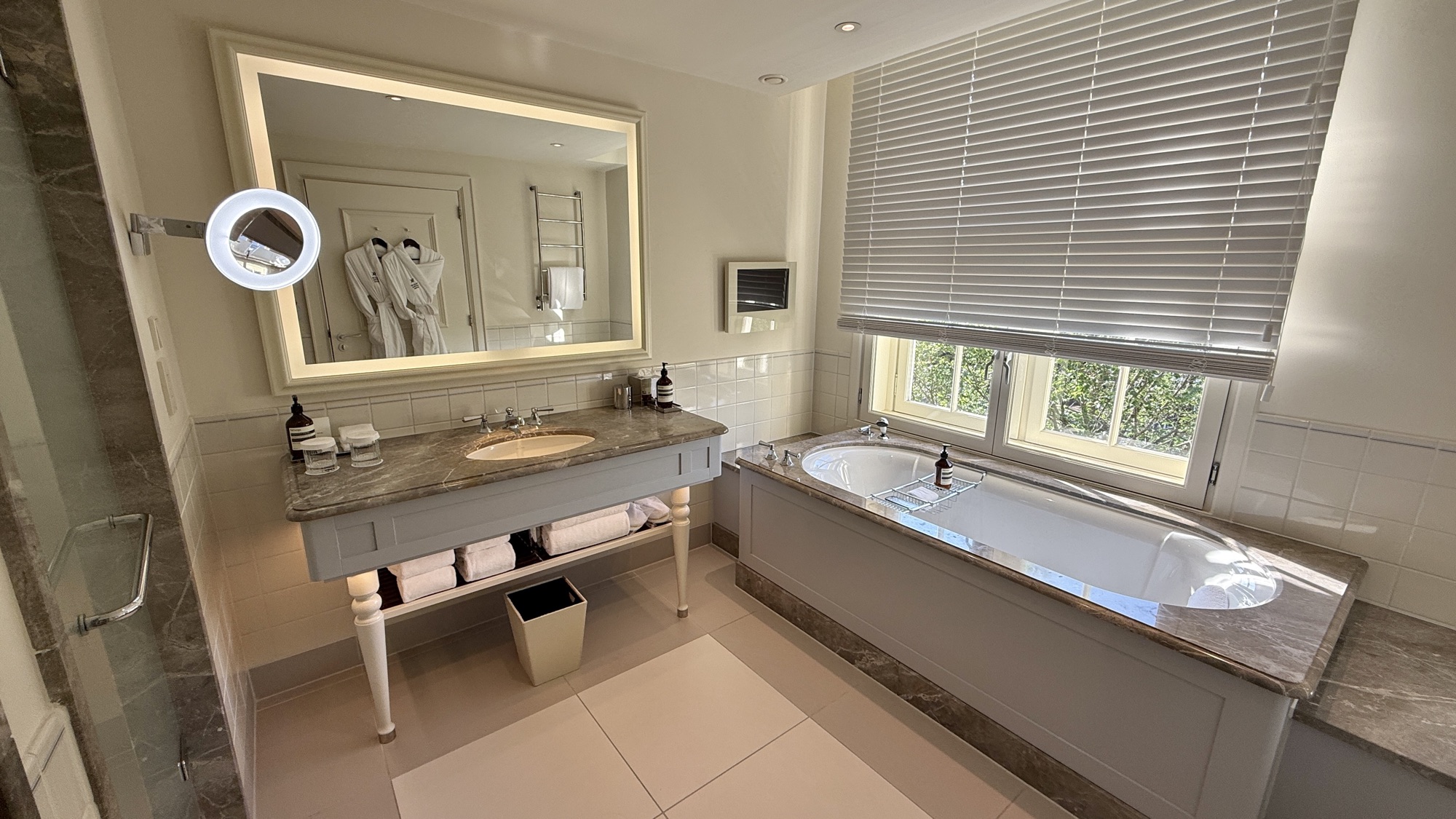 Bathroom with a lit vanity mirror and a bathtub set by the window in the King Grand Premier room