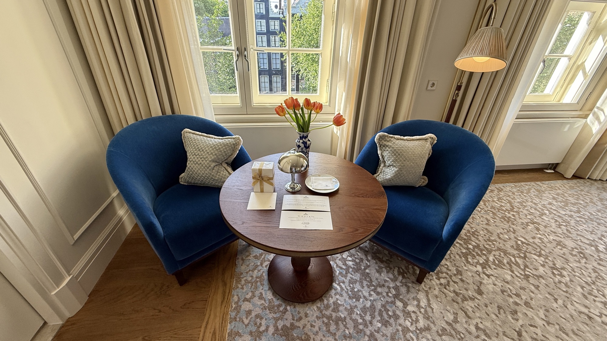 Two blue armchairs and a round table with fresh tulips by the windows in the King Grand Premier room
